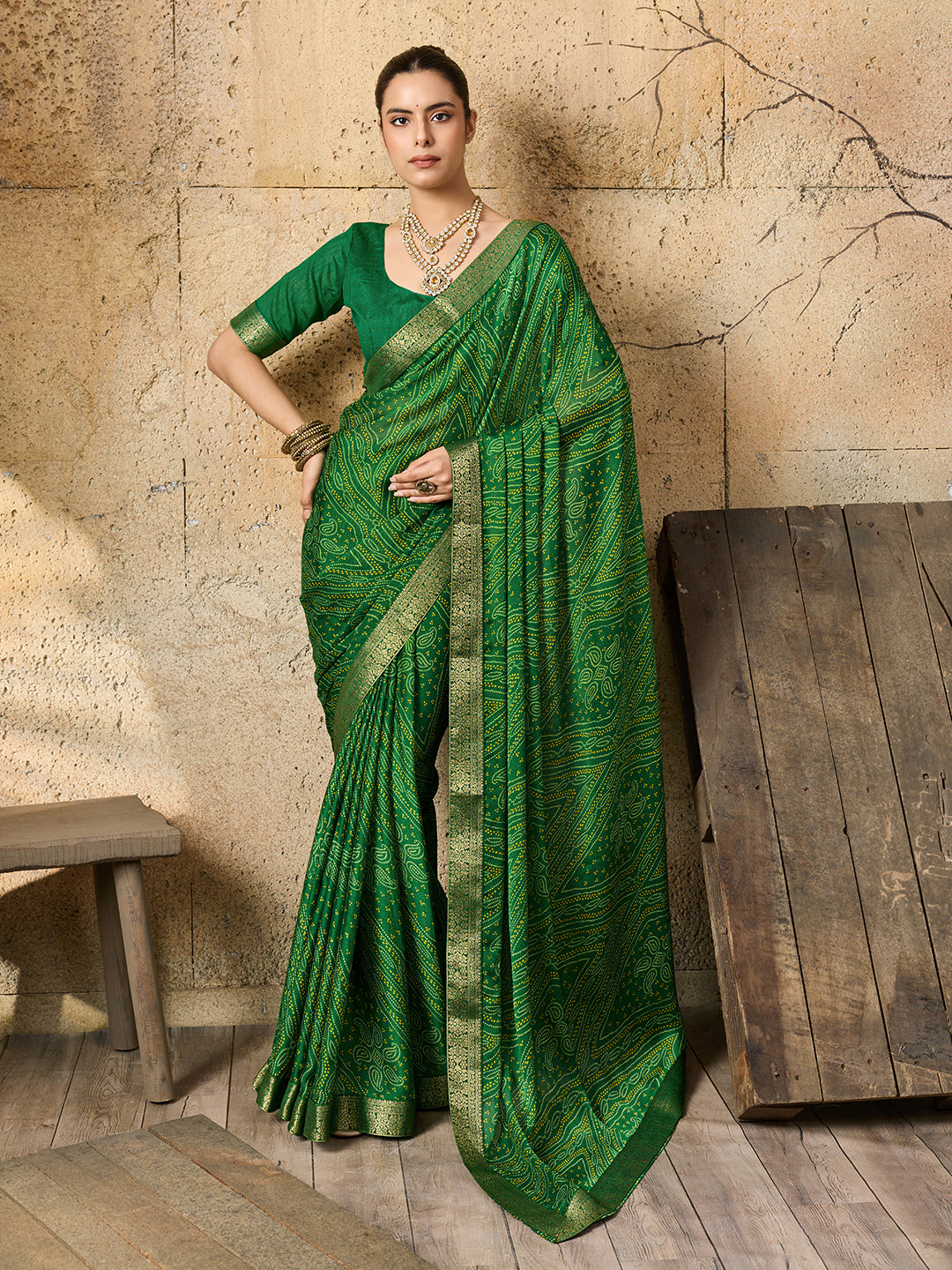 A green bandhani style chiffon georgette saree with a golden border and a matching green blouse piece,