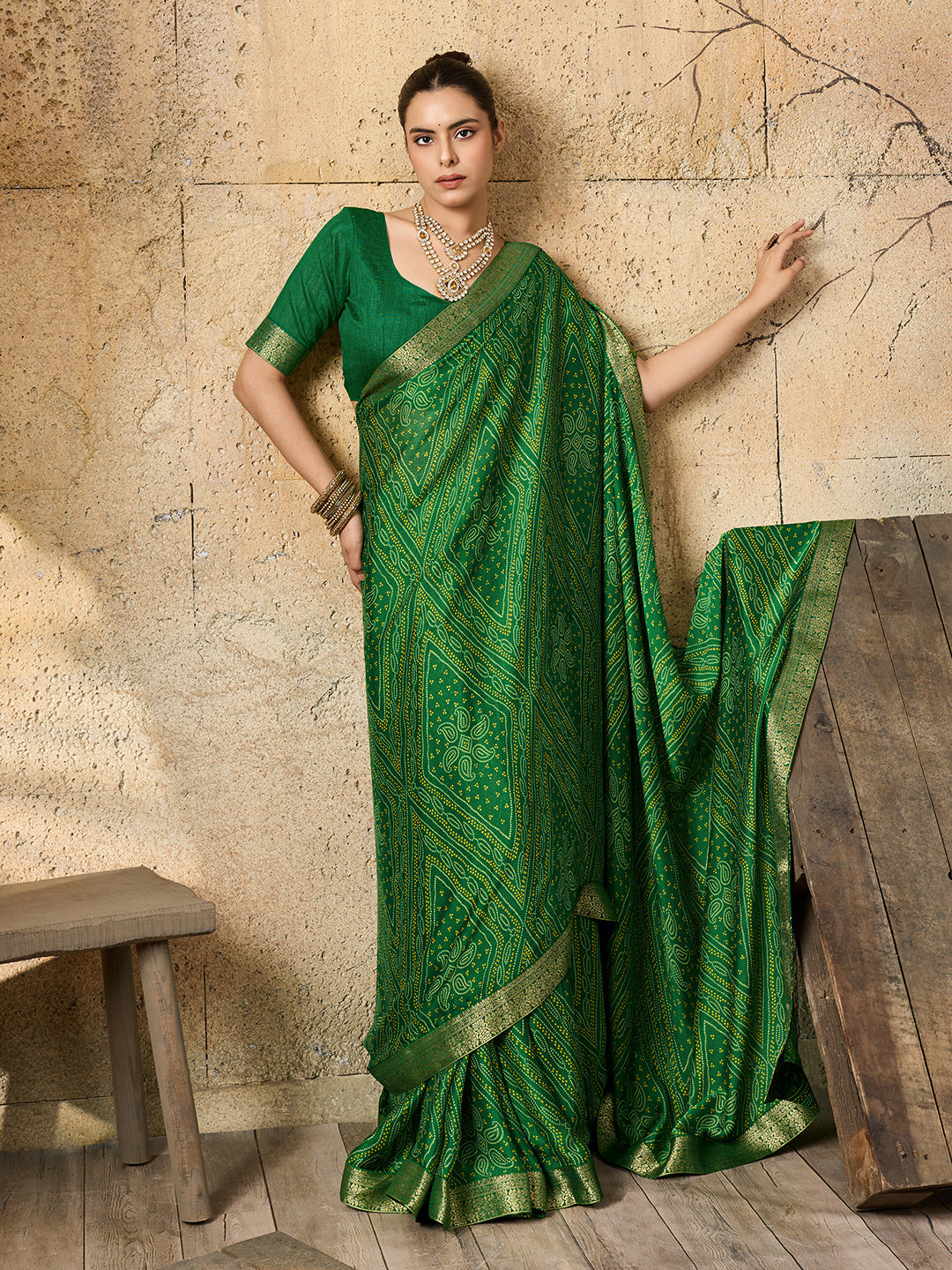 A green bandhani style chiffon georgette saree with a golden border and a matching green blouse piece,