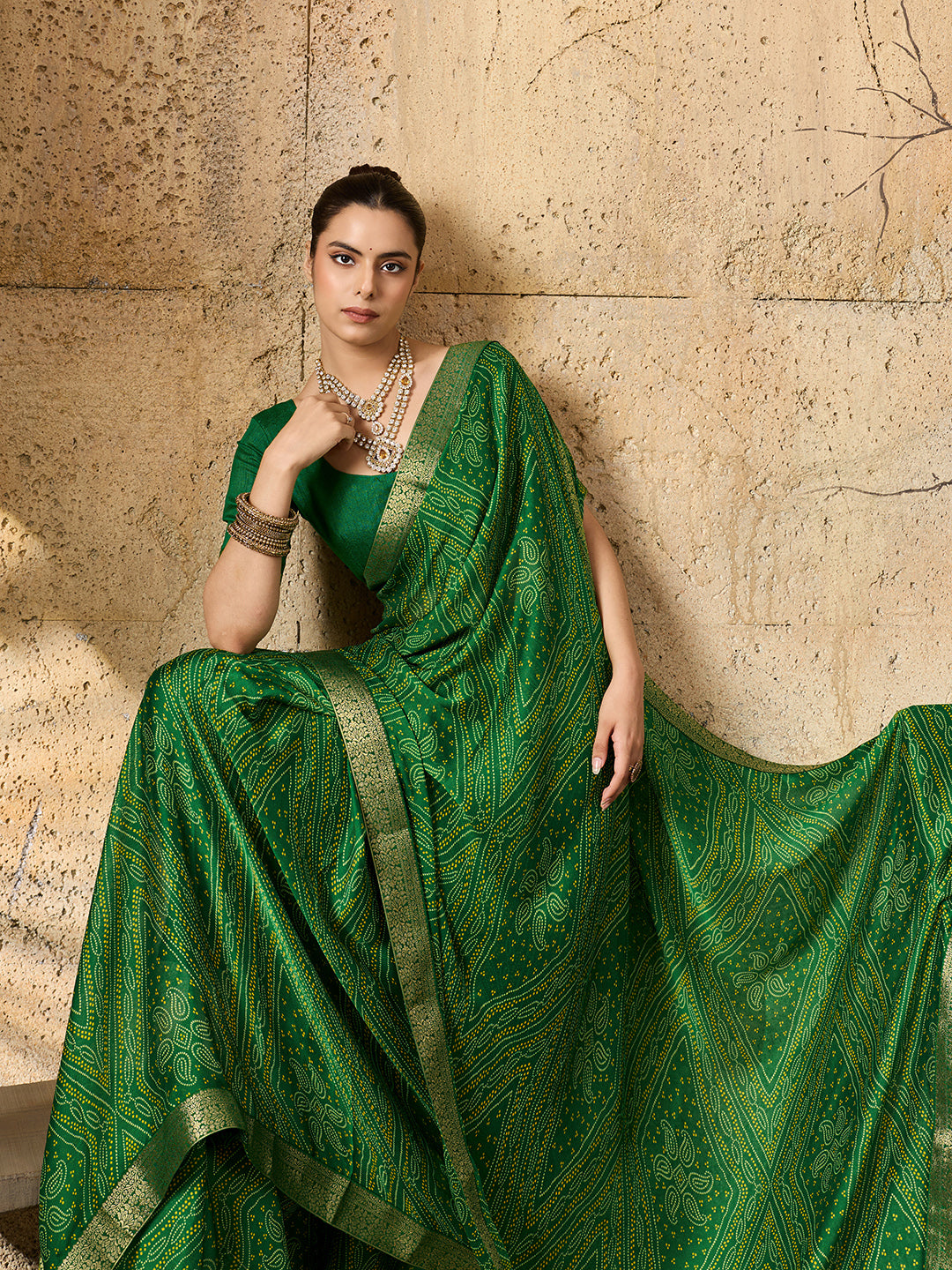 A green bandhani style chiffon georgette saree with a golden border and a matching green blouse piece,