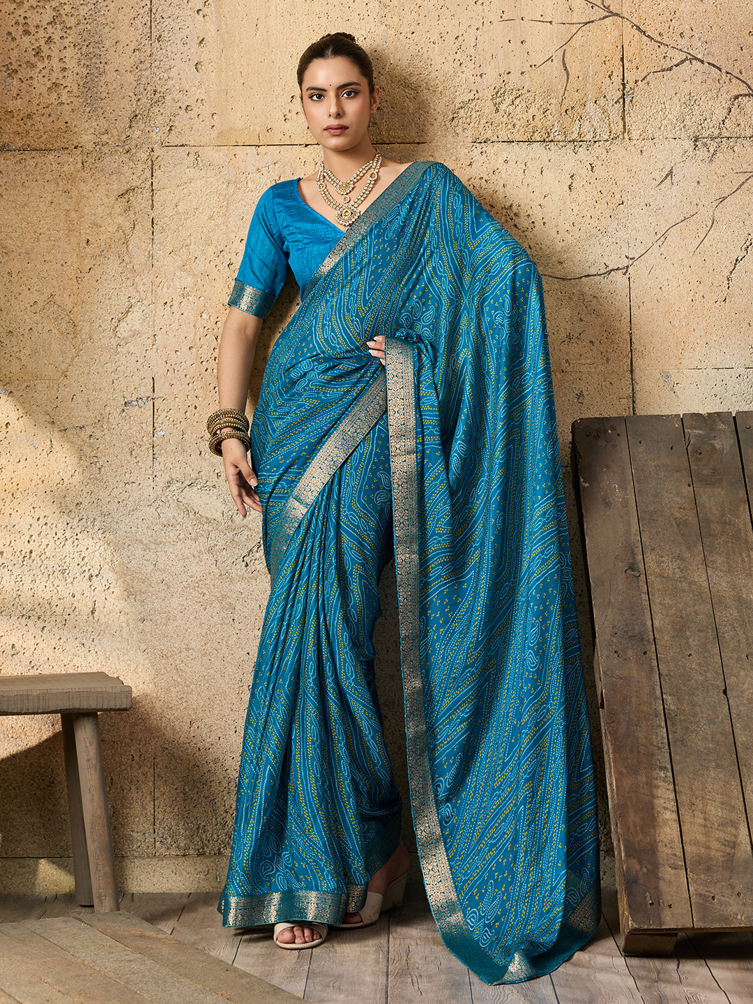A blue chiffon georgette saree with bandhani print, featuring a sky blue color and decorative patterns, paired with a blue blouse.