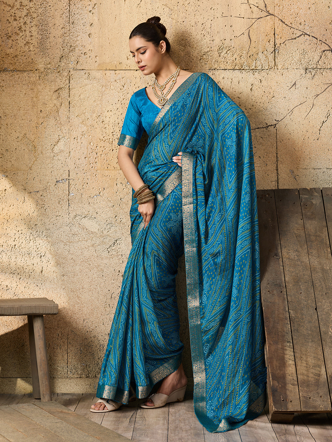 A blue chiffon georgette saree with bandhani print, featuring a sky blue color and decorative patterns, paired with a blue blouse.