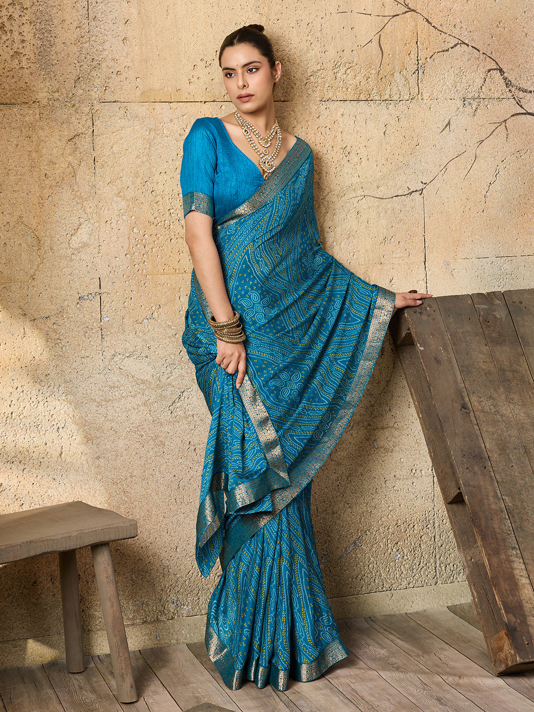 A blue chiffon georgette saree with bandhani print, featuring a sky blue color and decorative patterns, paired with a blue blouse.