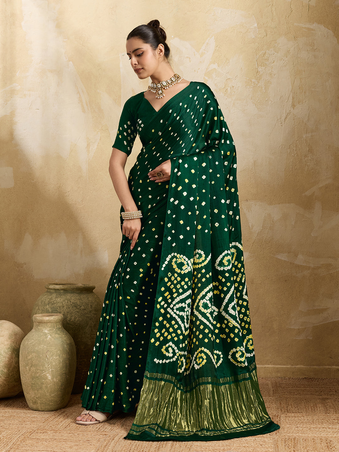 A bottle green saree with bandhani print and lagdi patola pallu, alongside a blouse piece.