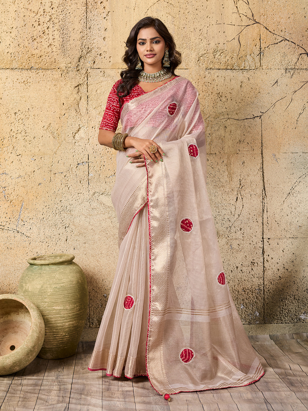 A white saree with red beads work and cutdana embellishments.