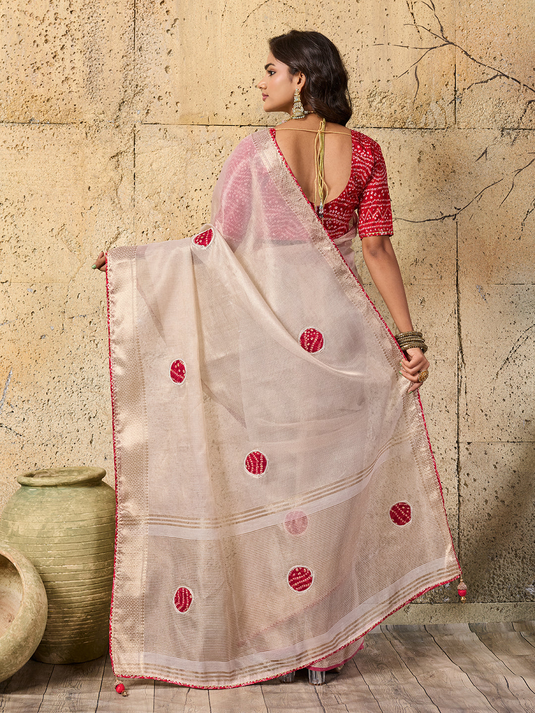 A white saree with red beads work and cutdana embellishments.
