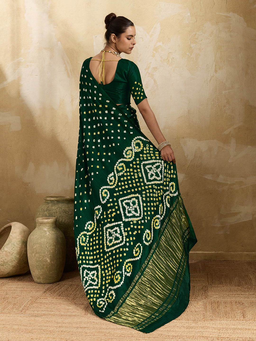 A bottle green saree with bandhani print and lagdi patola pallu, alongside a blouse piece.