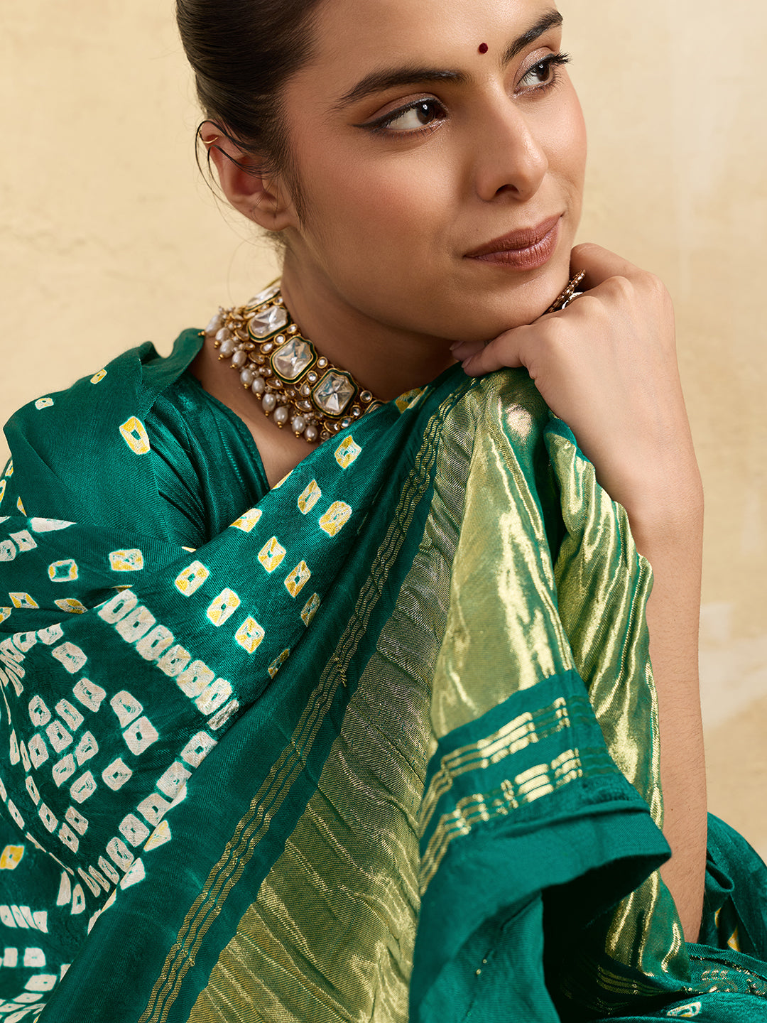 A traditional saree with a bandhani pattern in teal color,