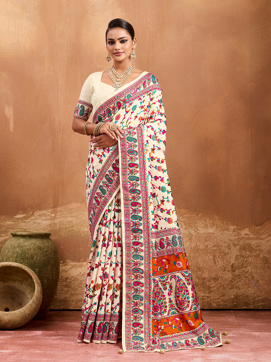 off-white saree with a floral and geometric pattern, featuring a heavy border and a small floral design on the fabric.