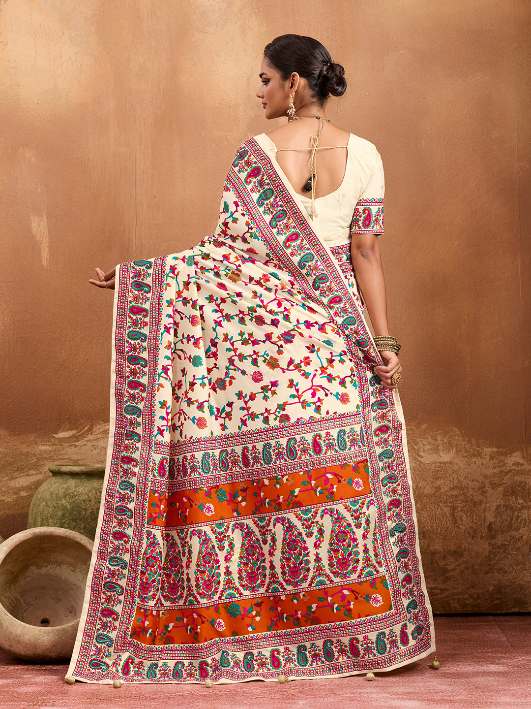 off-white saree with a floral and geometric pattern, featuring a heavy border and a small floral design on the fabric.