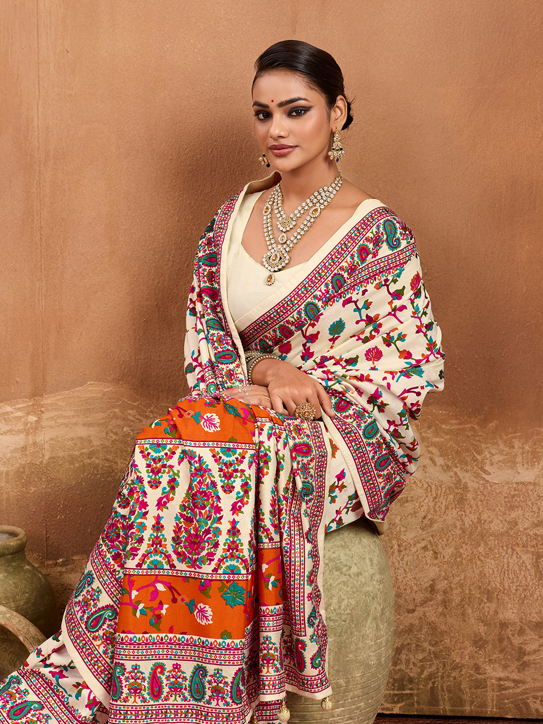 off-white saree with a floral and geometric pattern, featuring a heavy border and a small floral design on the fabric.