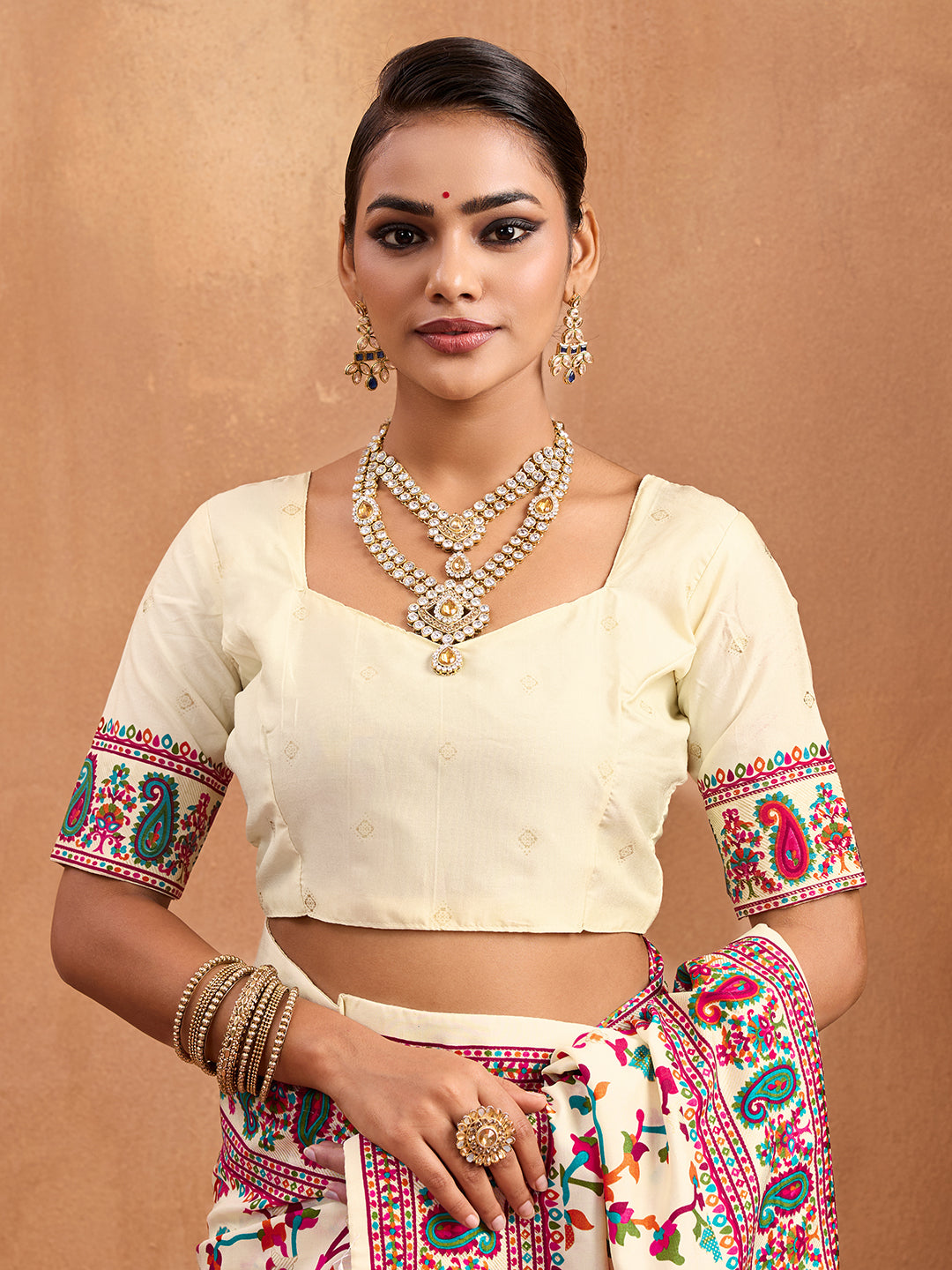 off-white saree with a floral and geometric pattern, featuring a heavy border and a small floral design on the fabric.