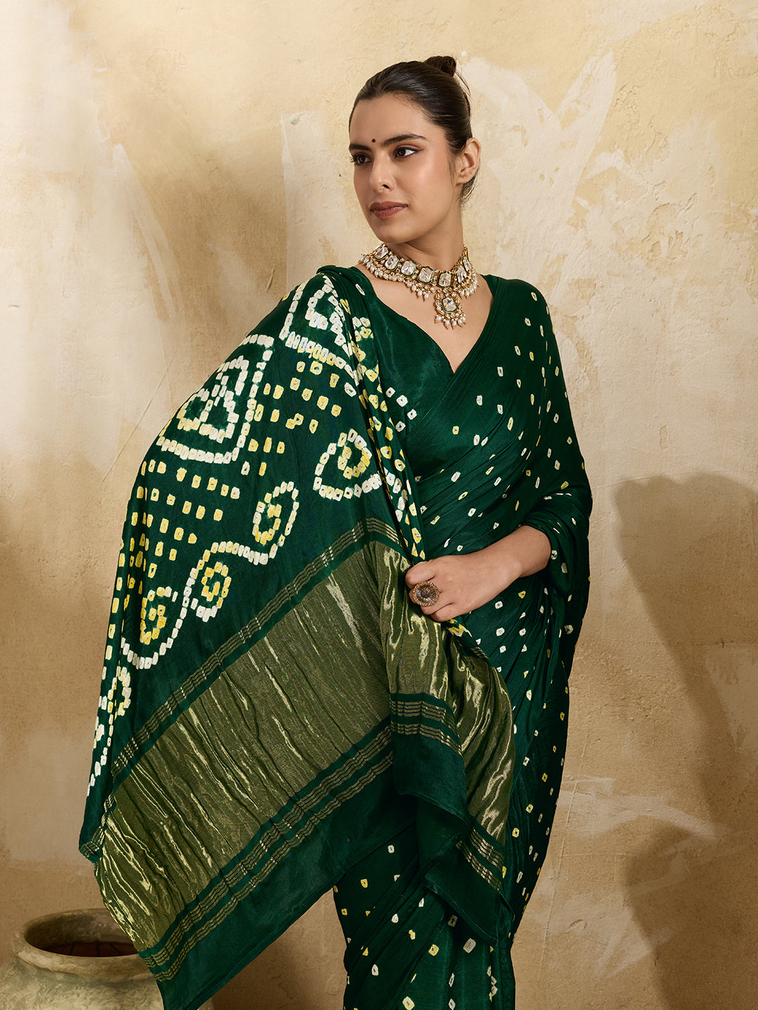 A bottle green saree with bandhani print and lagdi patola pallu, alongside a blouse piece.