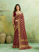 A maroon and gold Banarasi silk saree with heavy zari work (embroidery) and mirror handwork. The saree is traditional wear, likely used for festive or bridal occasions.