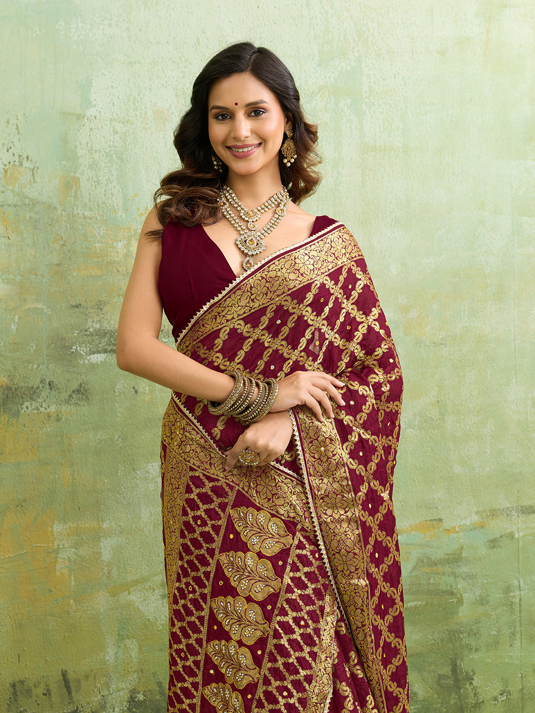A maroon and gold Banarasi silk saree with heavy zari work (embroidery) and mirror handwork. The saree is traditional wear, likely used for festive or bridal occasions.