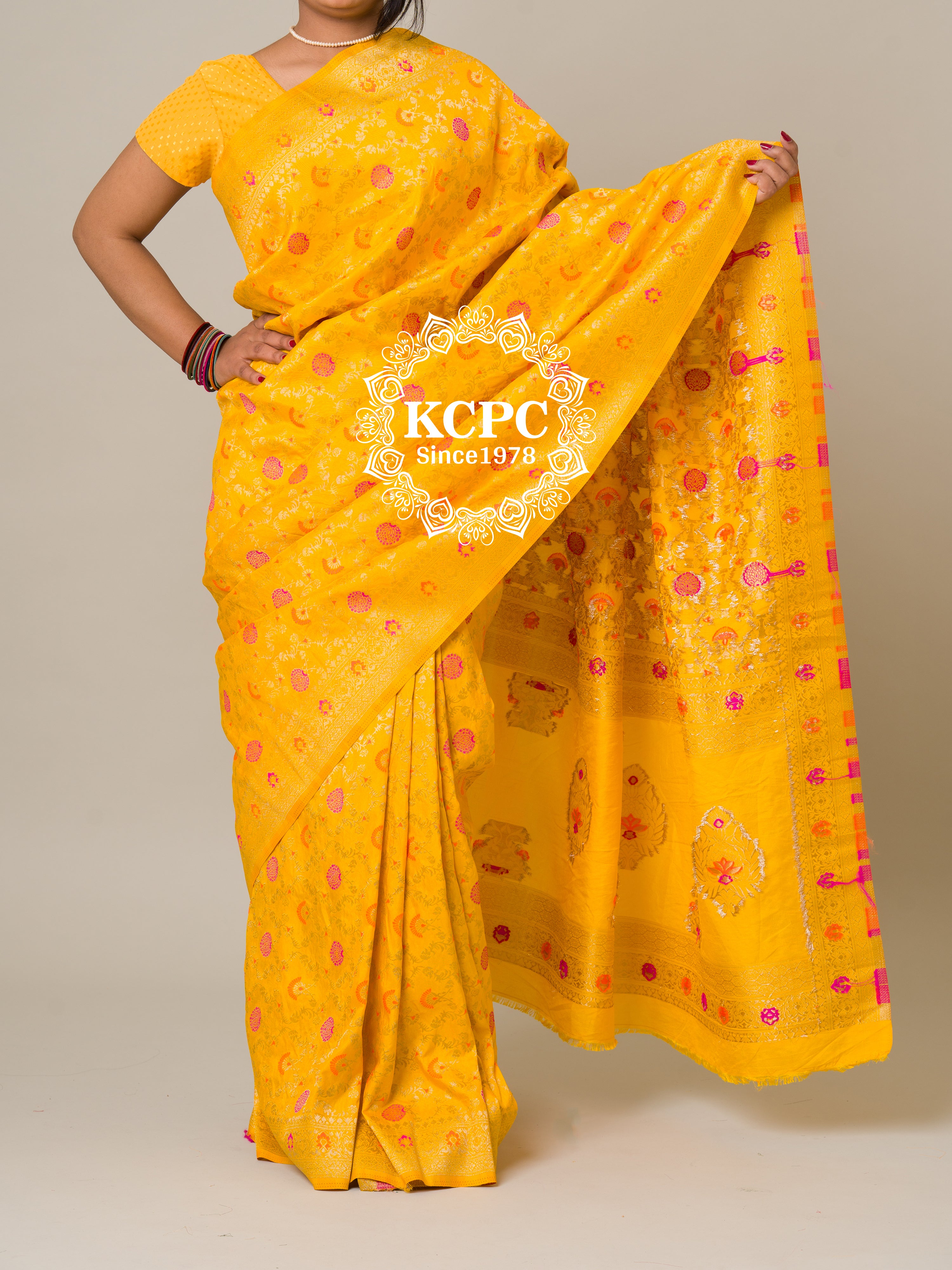 A yellow banarasi silk saree with floral patterns and zari embellishments.