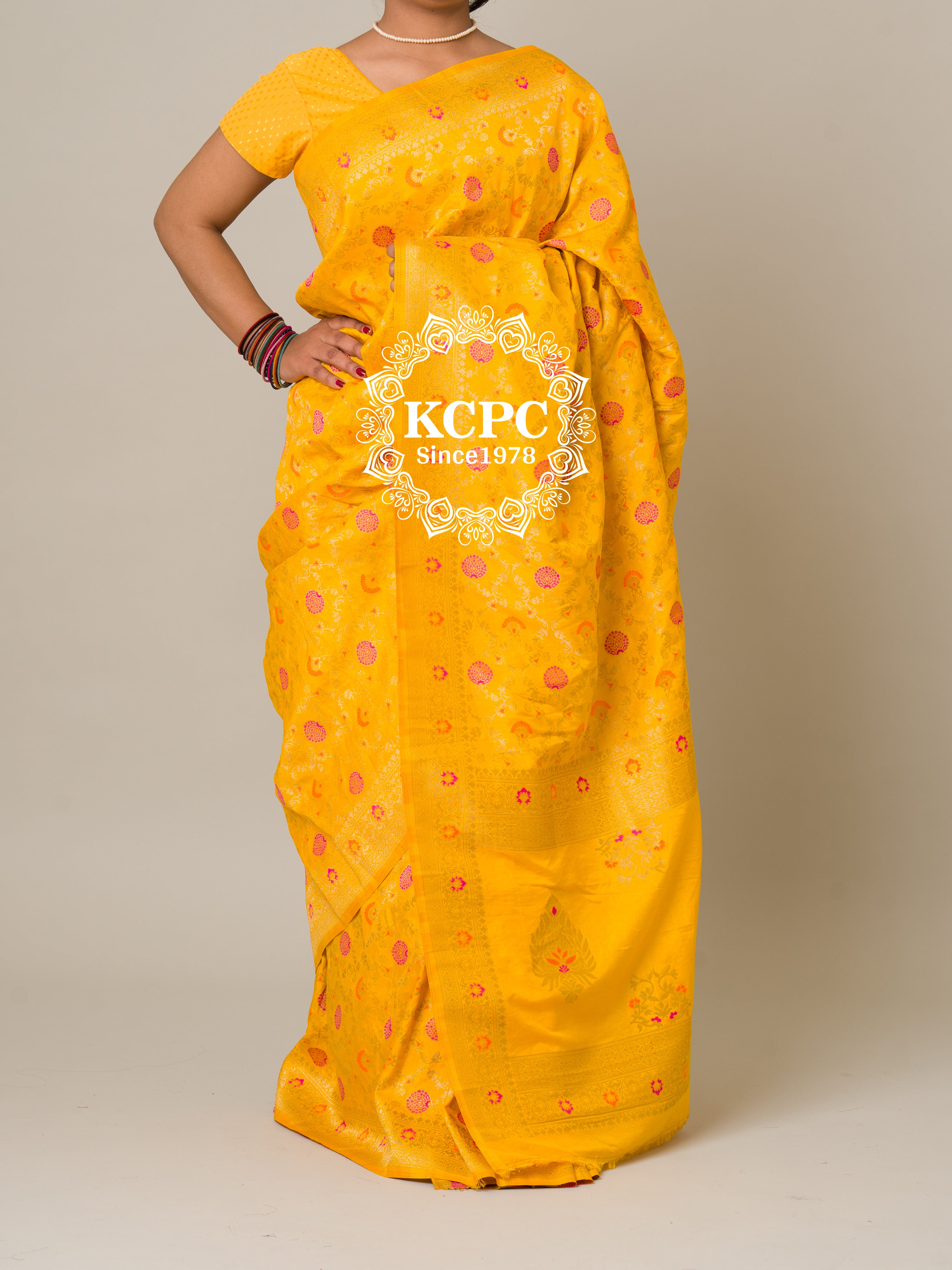 A yellow banarasi silk saree with floral patterns and zari embellishments.