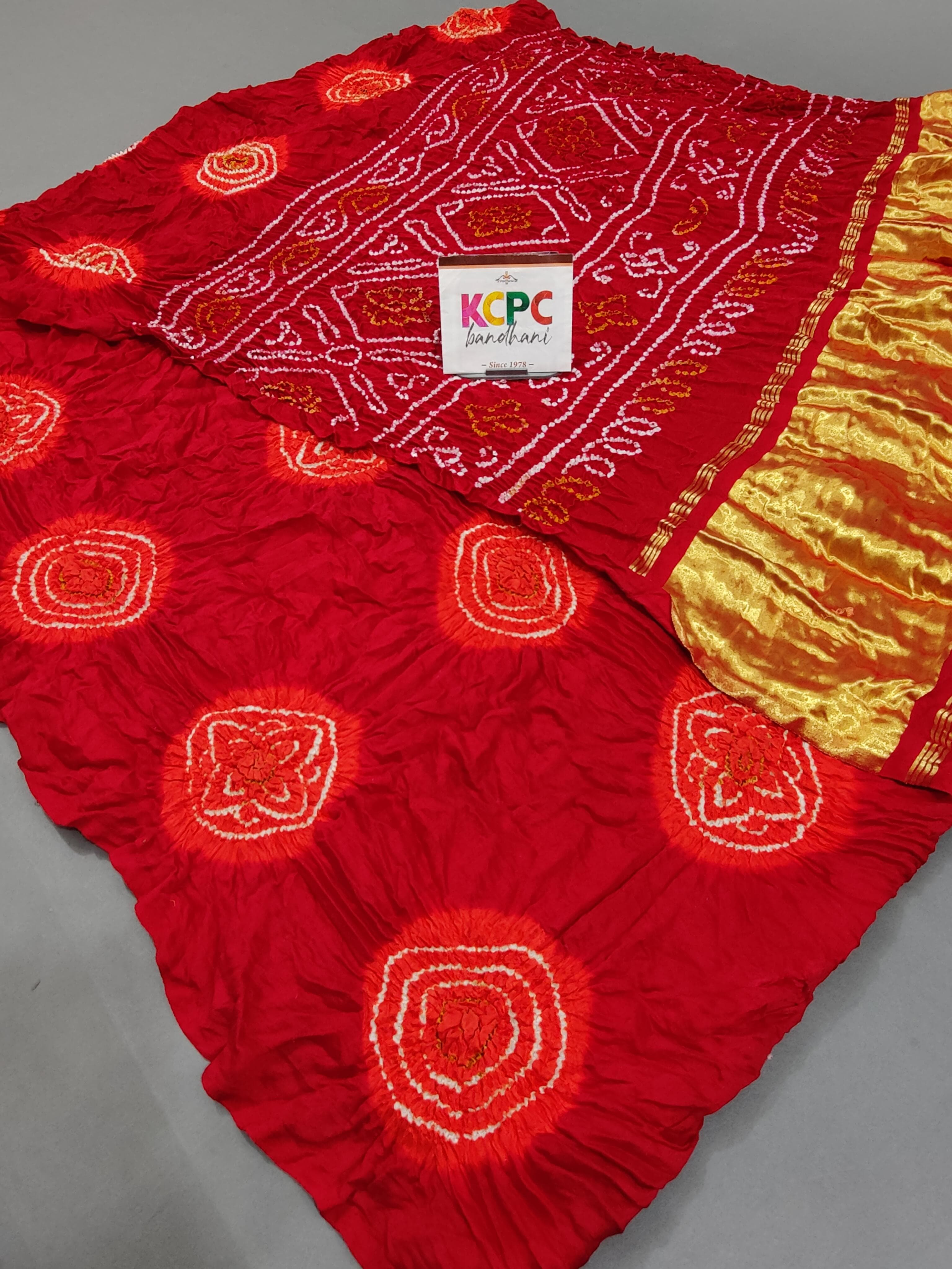 A red silk bandhani saree with yellow zari embellishments