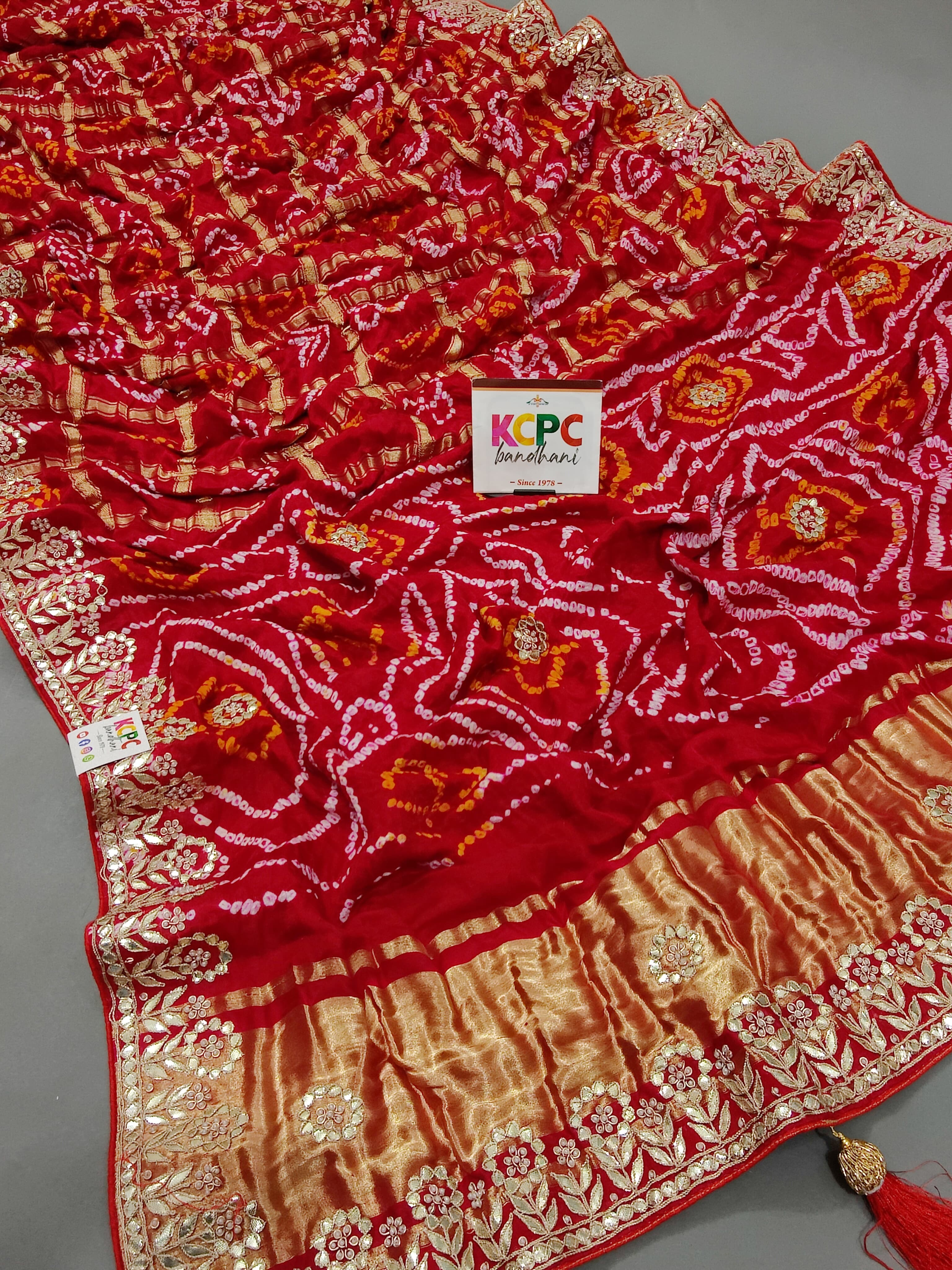 A red and gold silk saree with bandhani style and gota patti