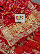 A red and gold silk saree with bandhani style and gota patti