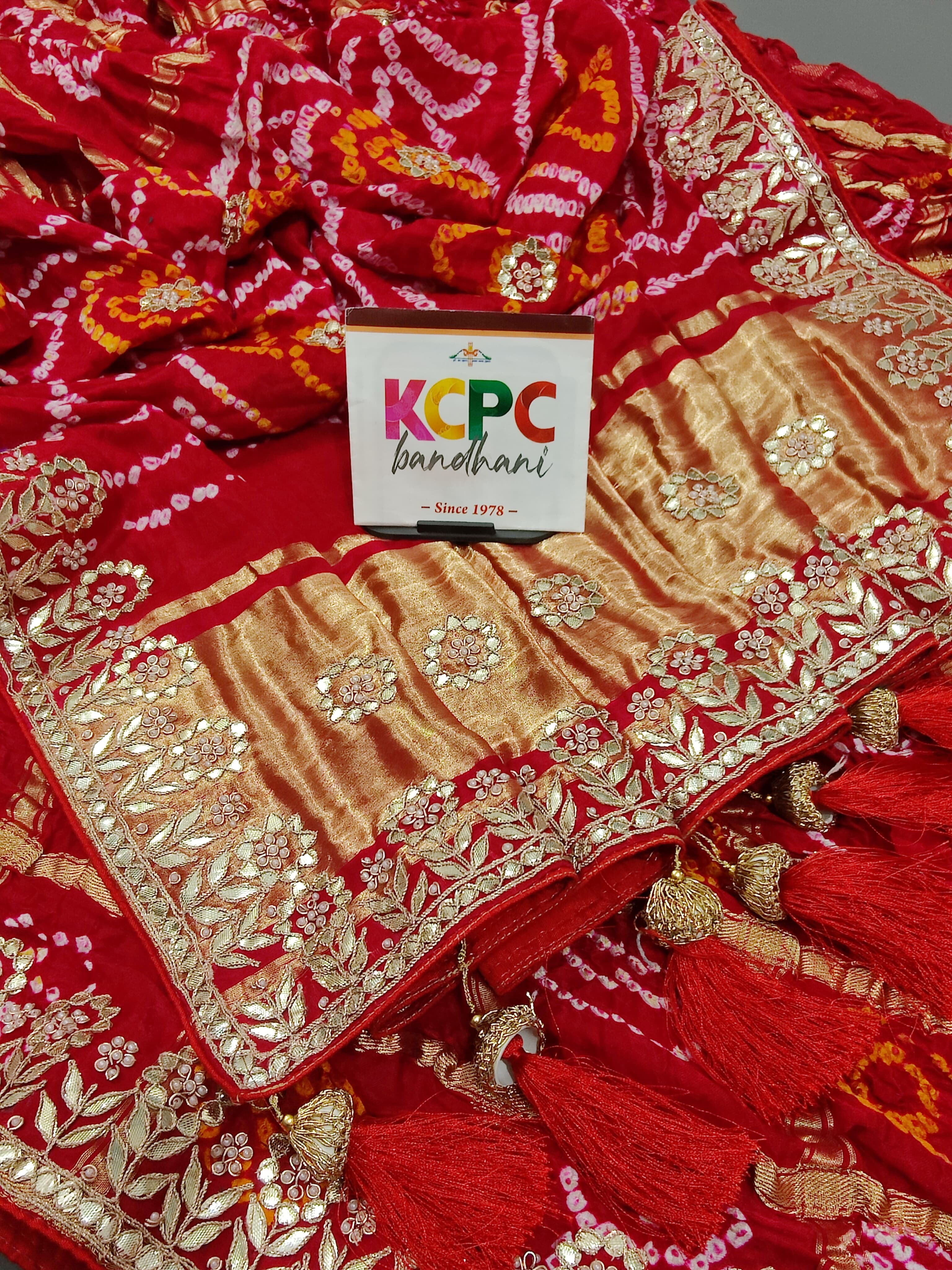 A red and gold silk saree with bandhani style and gota patti
