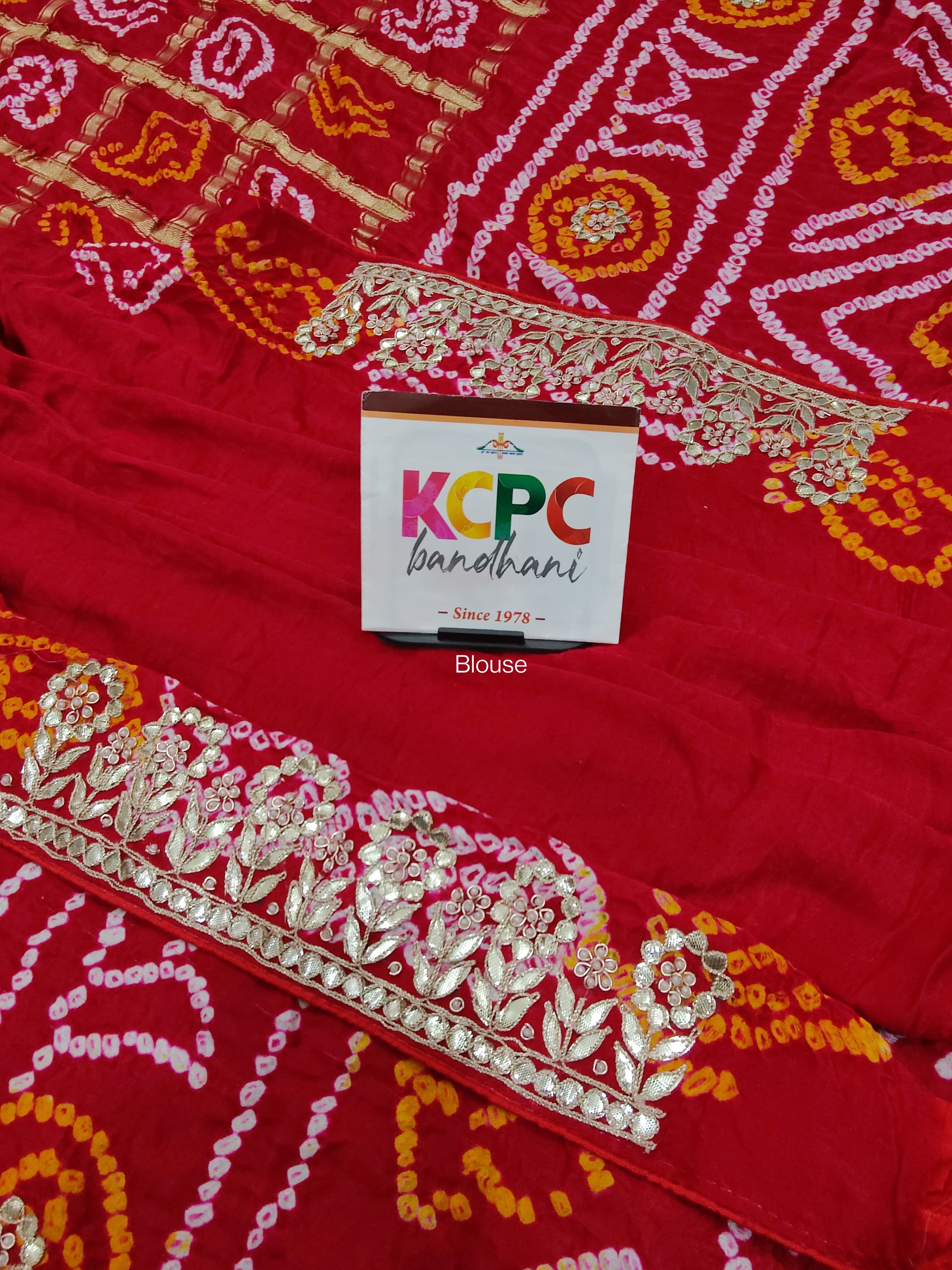 A red and gold silk saree with bandhani style and gota patti