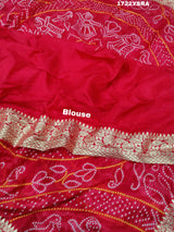 A pink and orange bandhani saree with a zari border