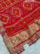 A red and gold saree with floral patterns and gota patti embellishments