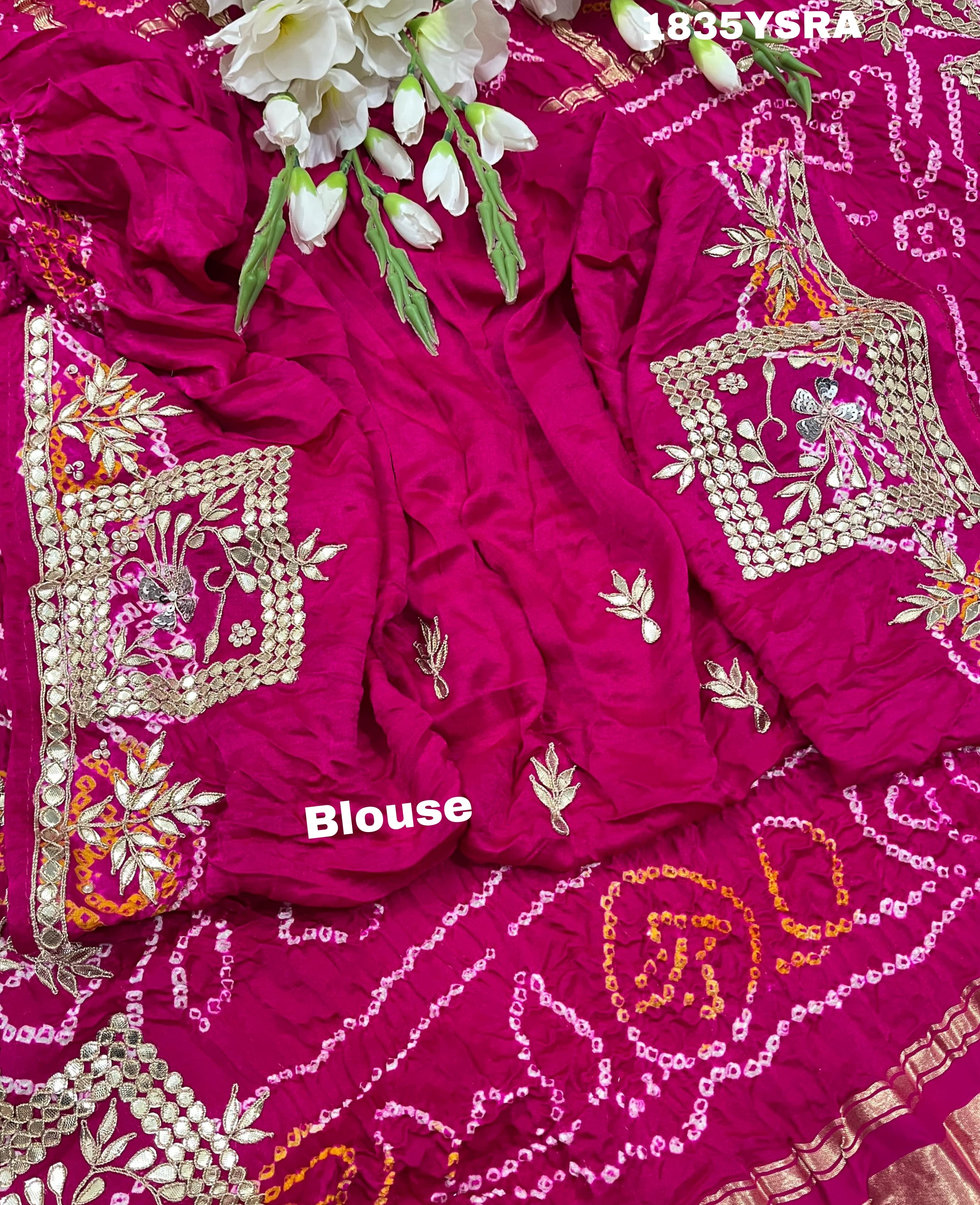 A pink and red silk saree with gota patti work and a floral embellishment