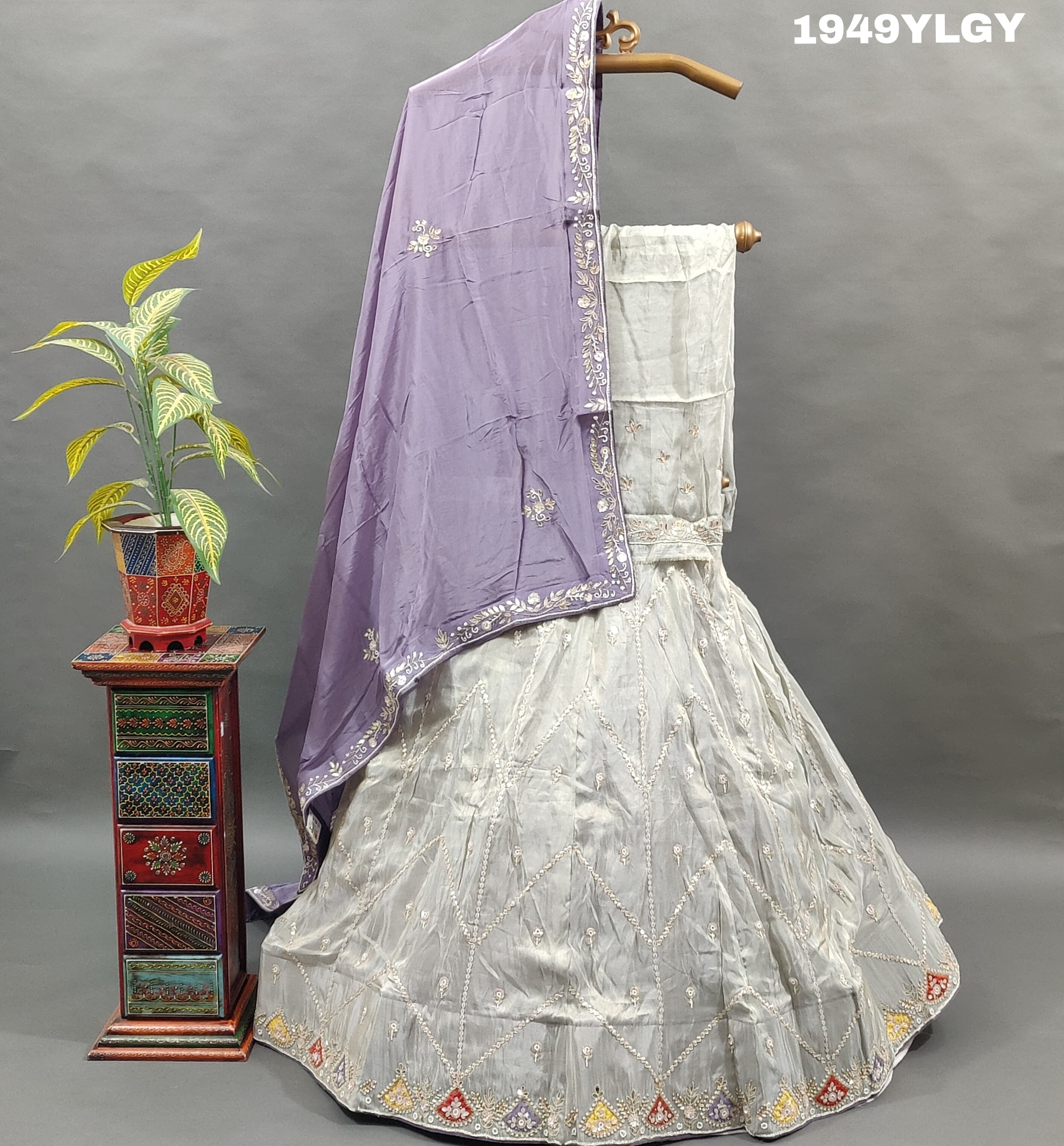 A traditional Indian lehenga set with white beadwork and a pastel pink Banarasi silk