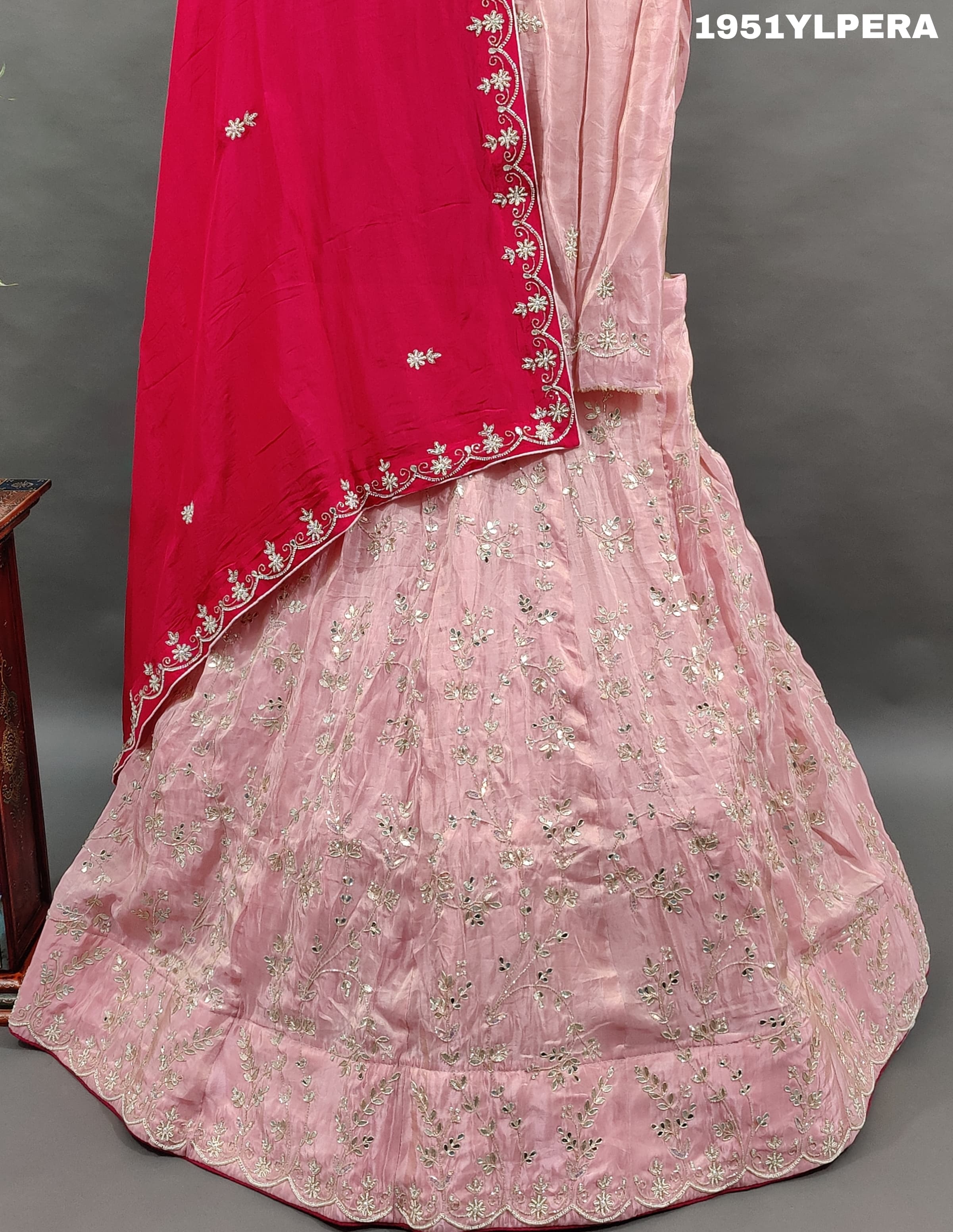 A pink traditional lehenga set with white beadwork and a red dupatta