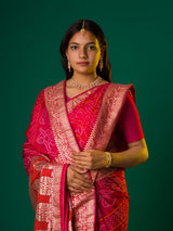 A pink and orange bandhani saree with a zari border