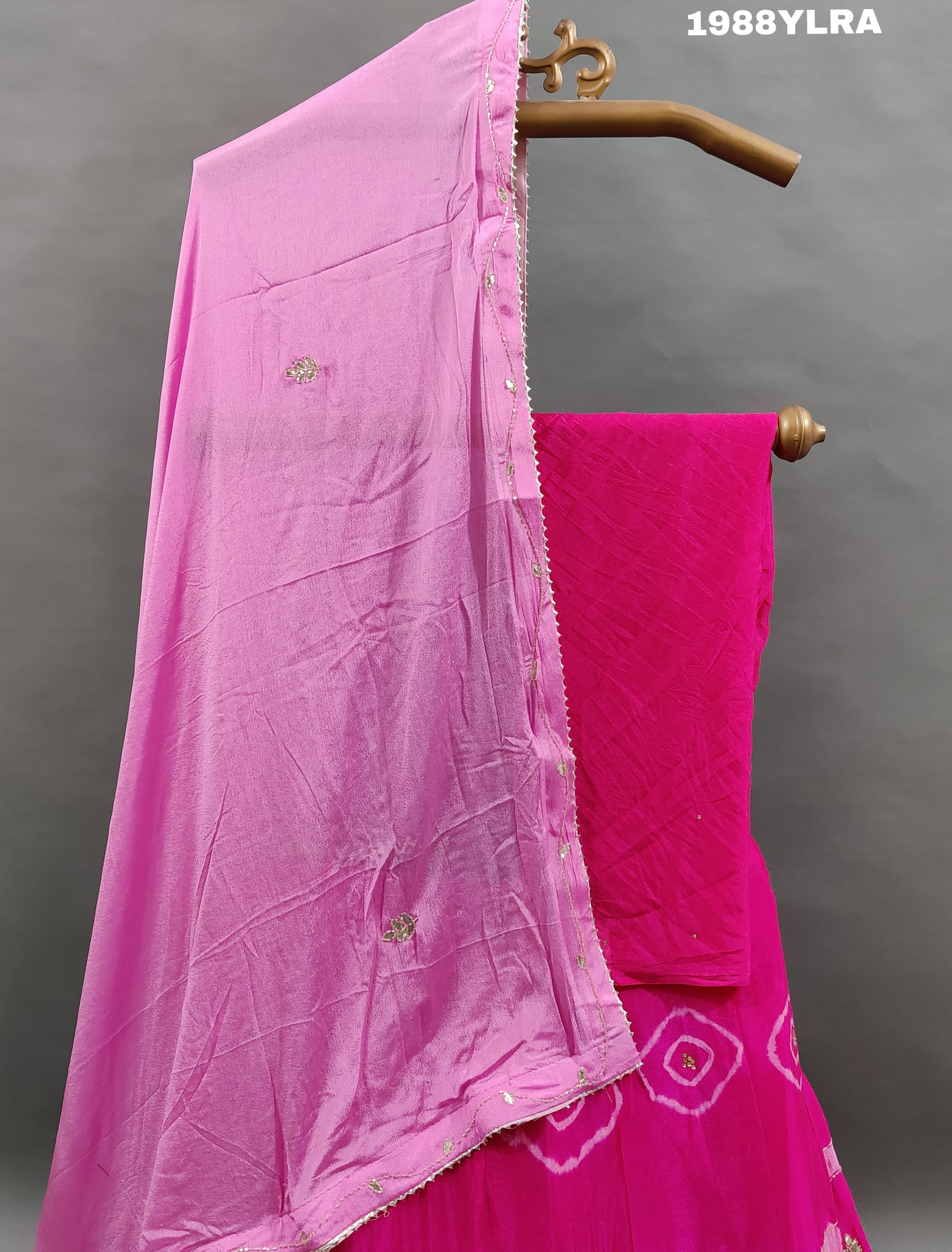 A traditional wear lehenga set with pink and white color bandhani style