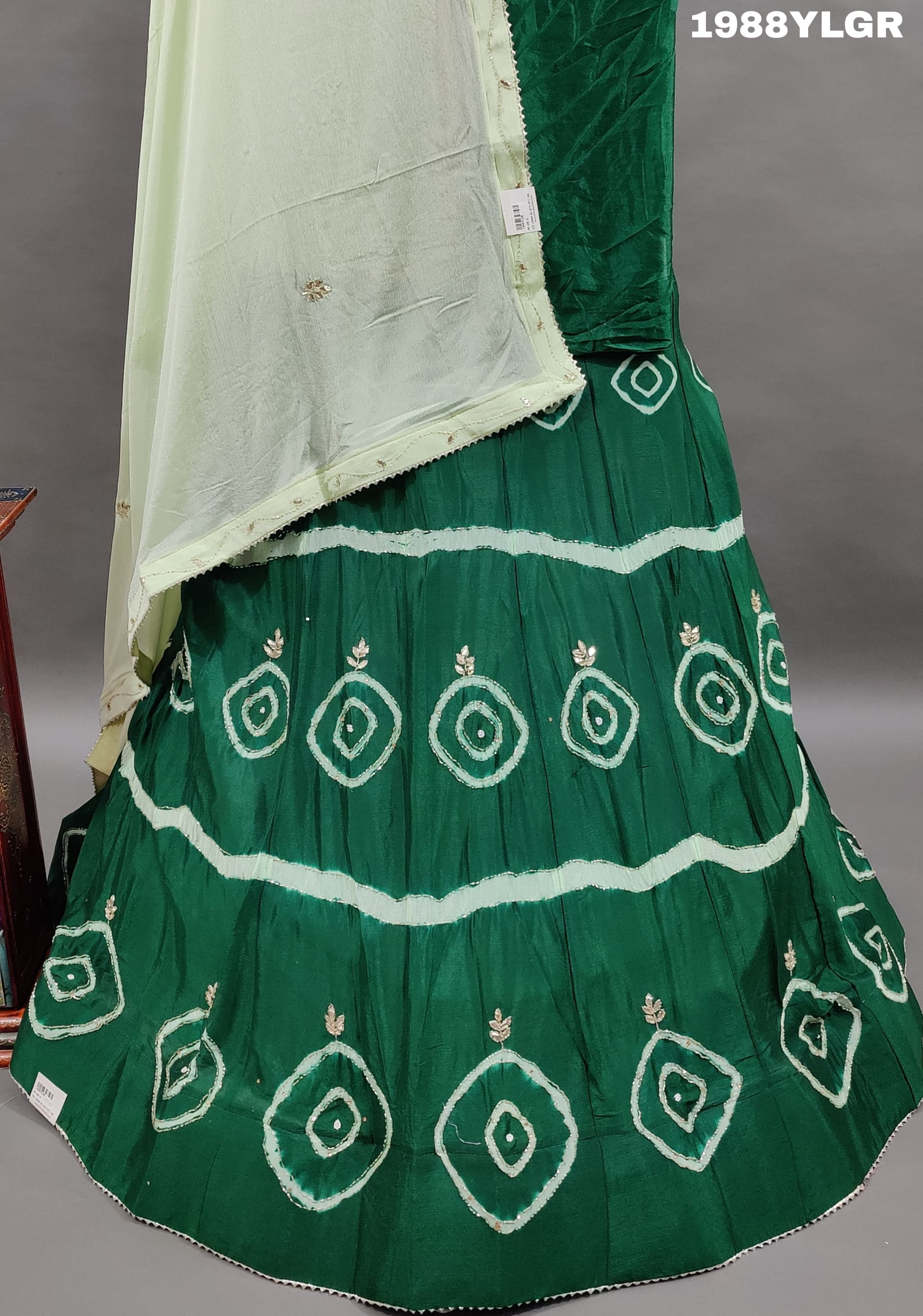 A green and white traditional wear lehenga set with tie-dye bandhani