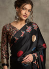 A black silk saree with red and blue ajrak print design and a golden border.