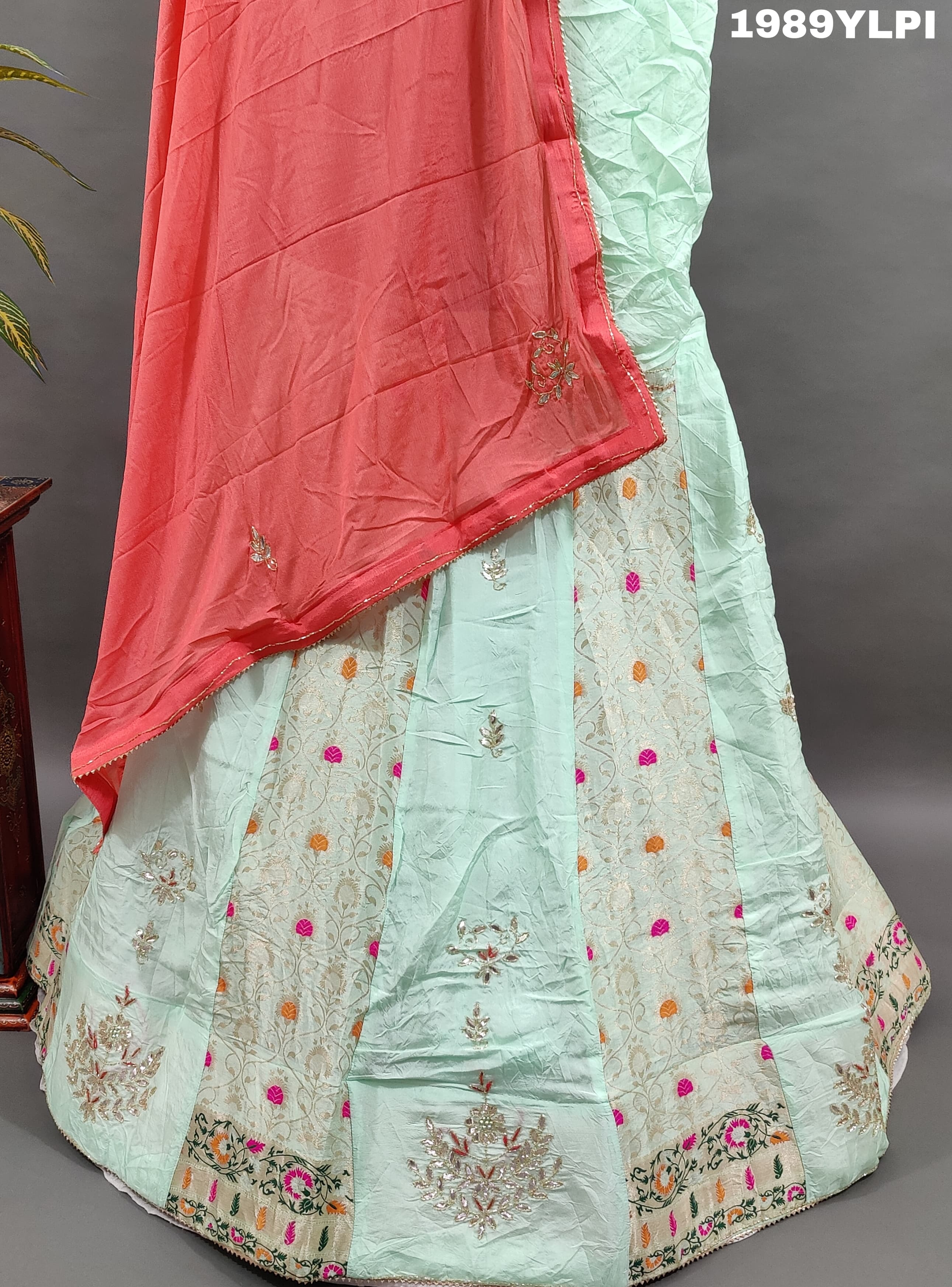 A lehenga set with a green and pink color cutdana work