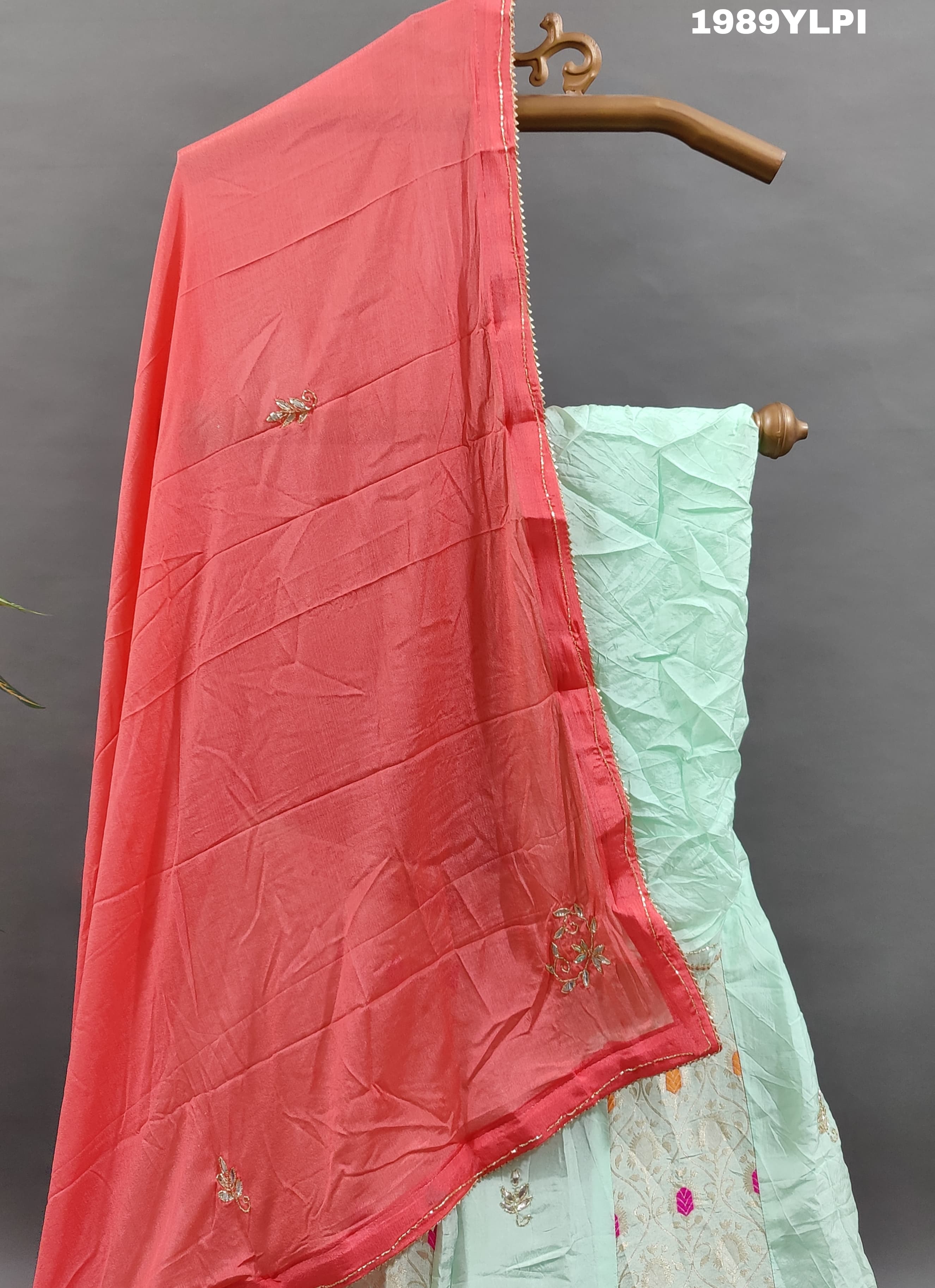 A lehenga set with a green and pink color cutdana work