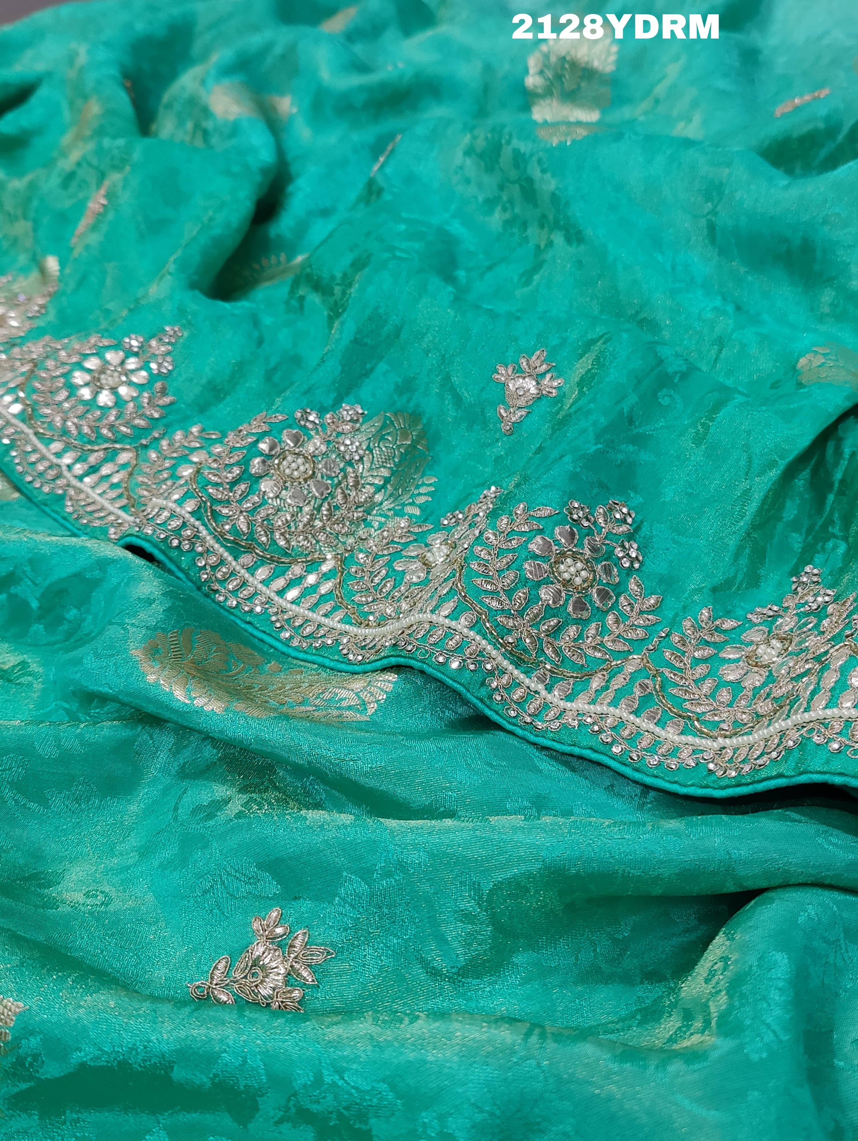 A green saree with red and silver paisley patterns and detailed embroidery,