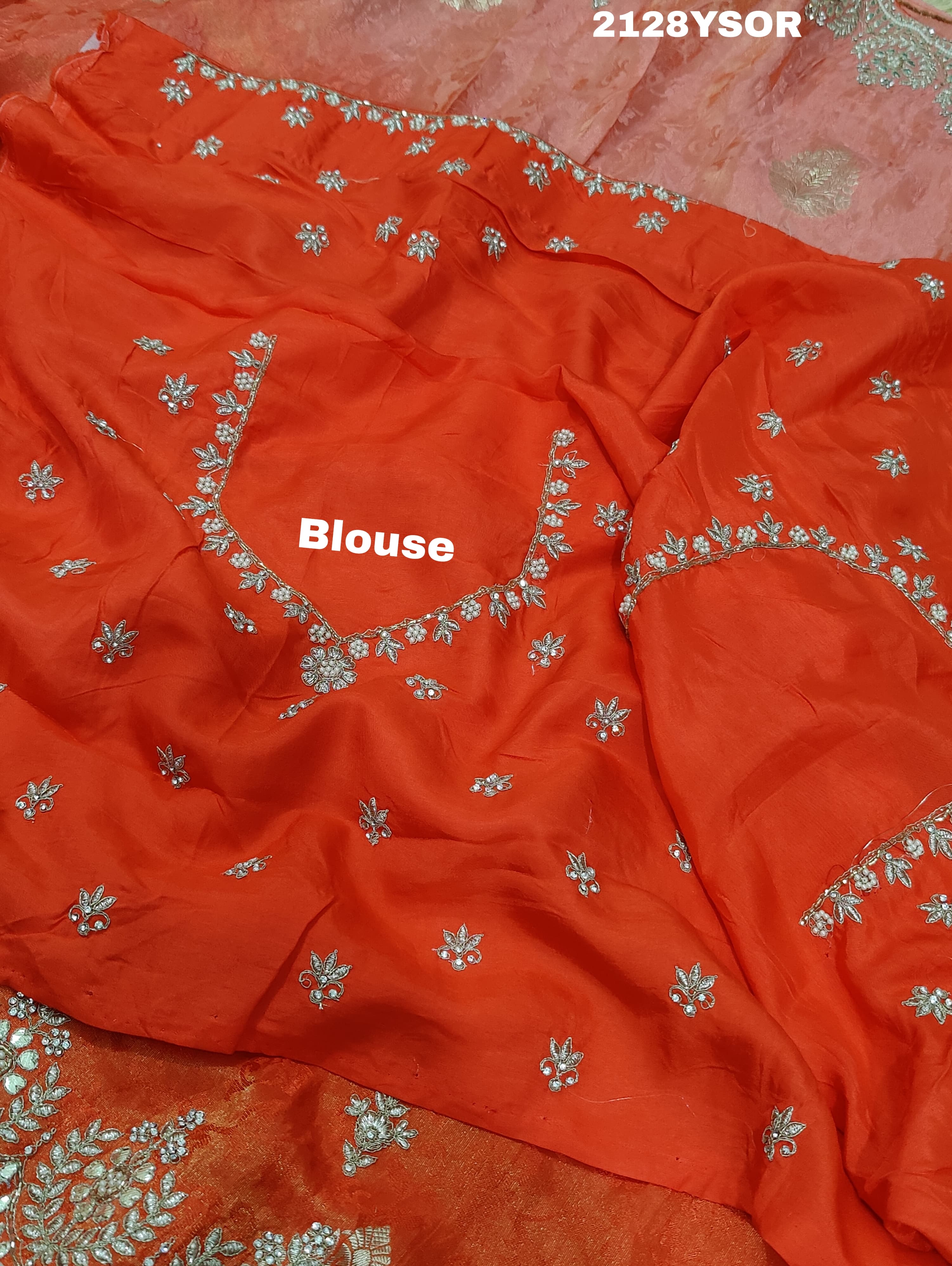 An orange saree with silver paisley pattern and floral gotapatti work, along with sequence embellishments.