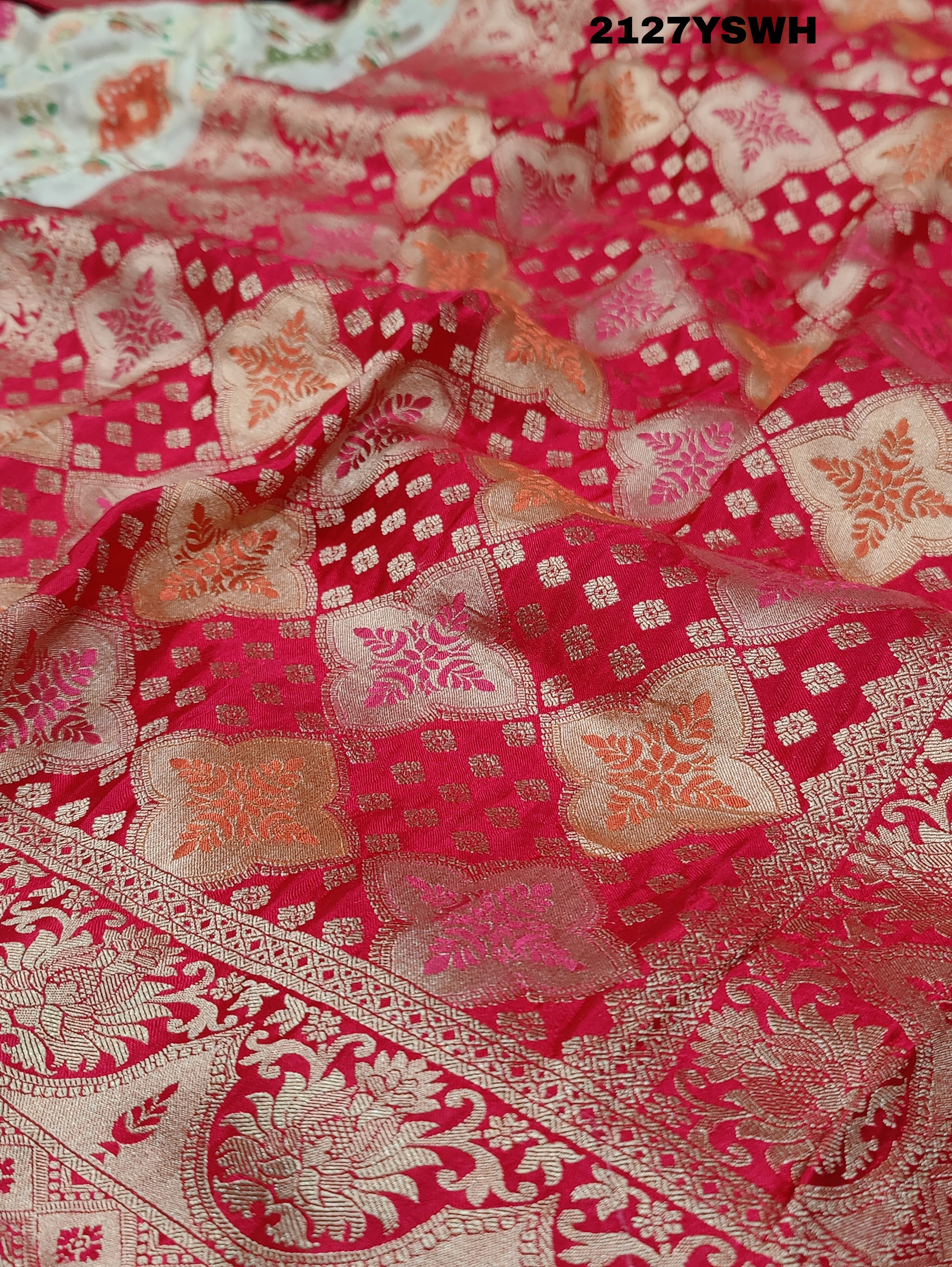 A Banarasi silk saree with a Meenakari pattern featuring a cream body with multicolor floral designs and a red border.