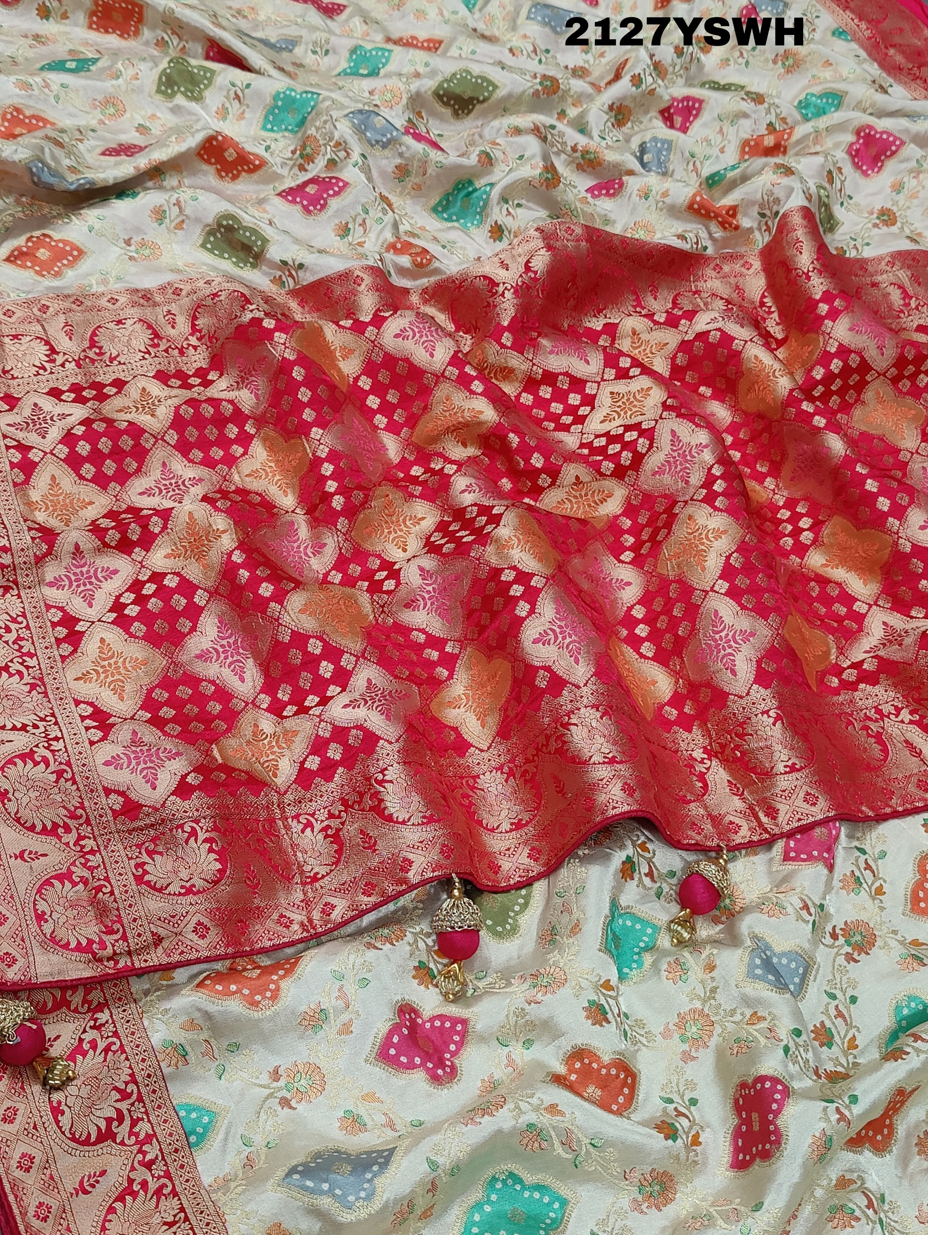 A Banarasi silk saree with a Meenakari pattern featuring a cream body with multicolor floral designs and a red border.