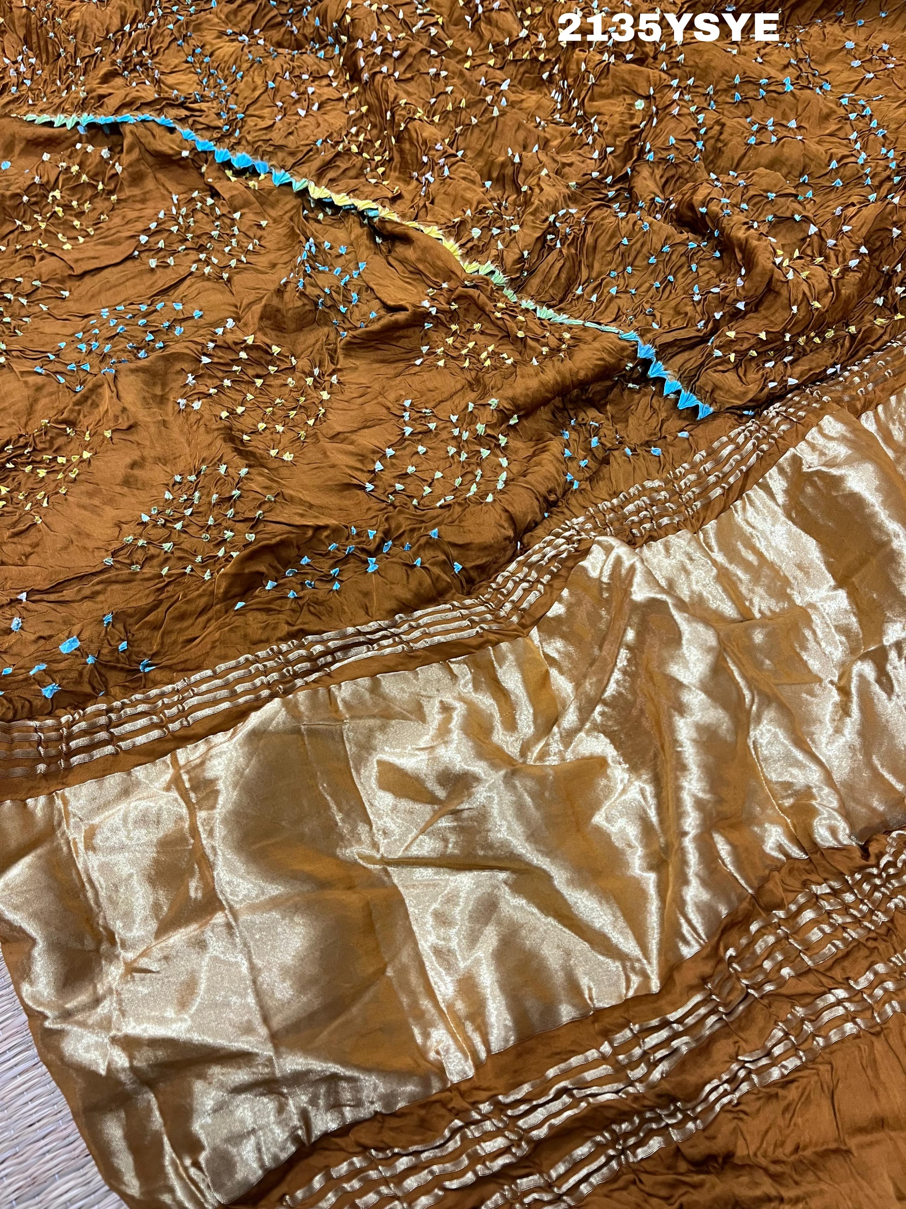 A brown and yellow silk saree with bandhani style dots and a metallic border.