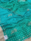 A green saree with bandhani pattern and cutdana work