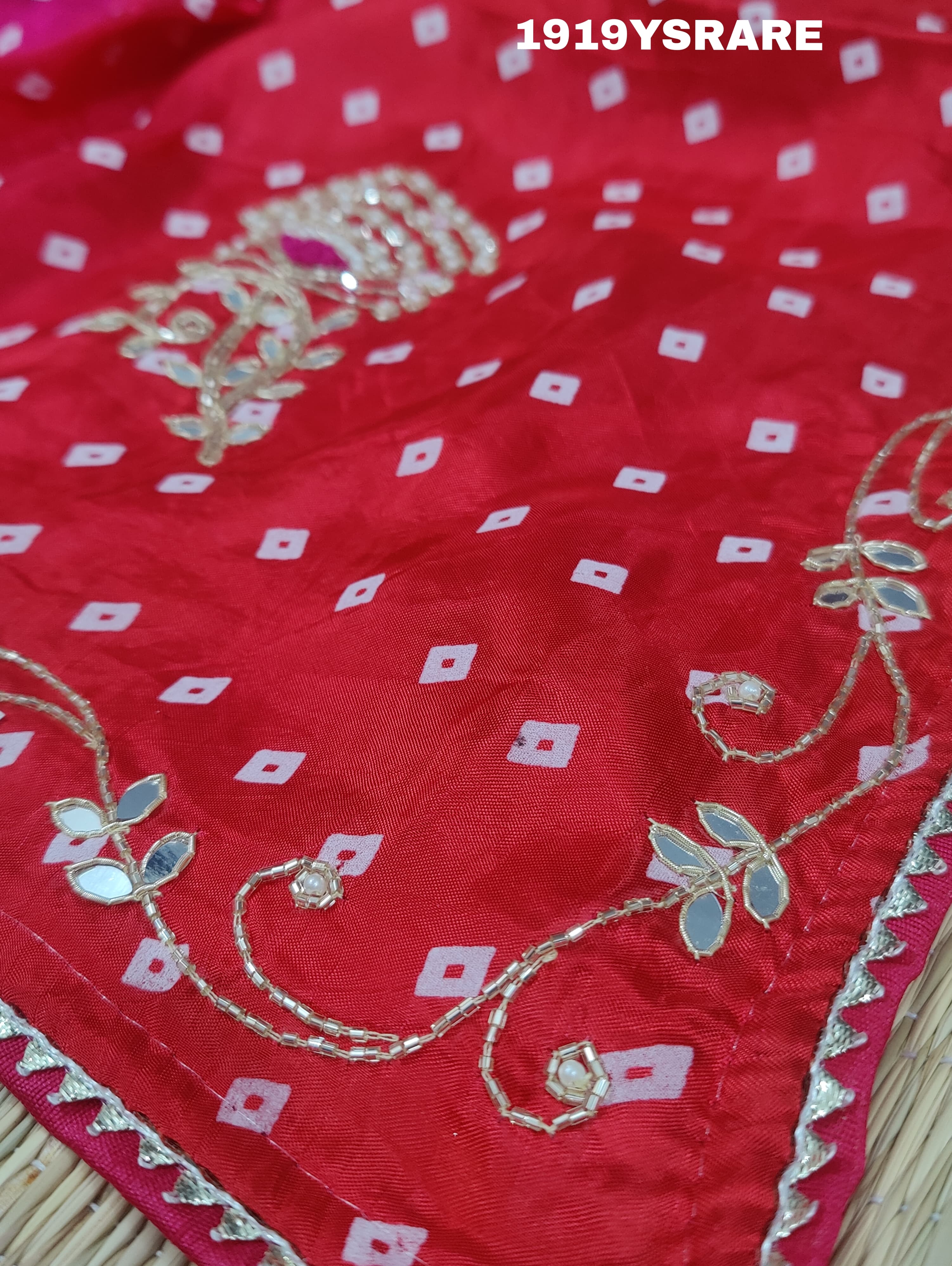 A saree with a bandhani pattern and cutdana work, predominantly pink with red accents.