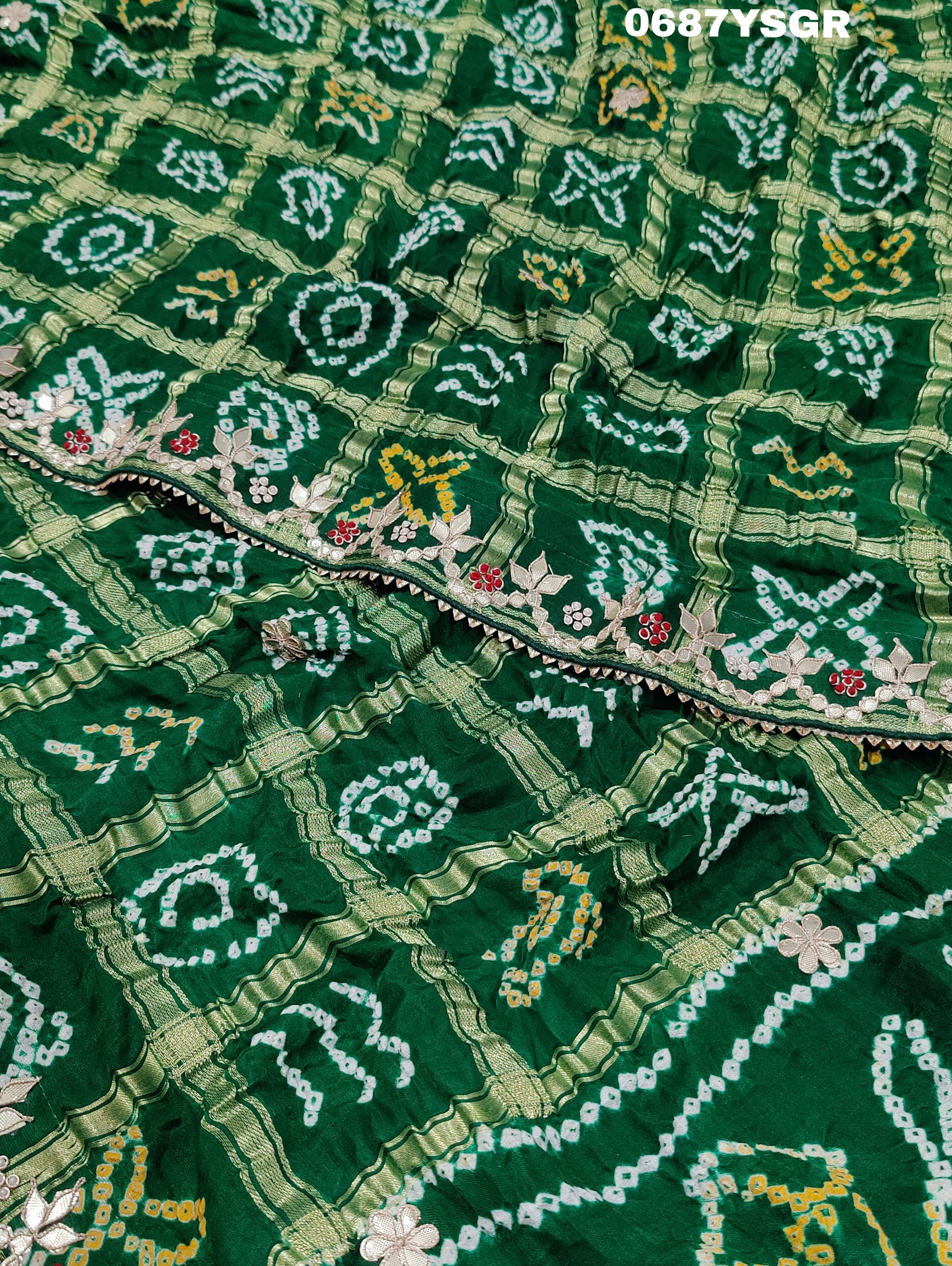 A green and silver pure gaji silk saree with bandhani pattern and gotapatti handwork, displayed on a surface.