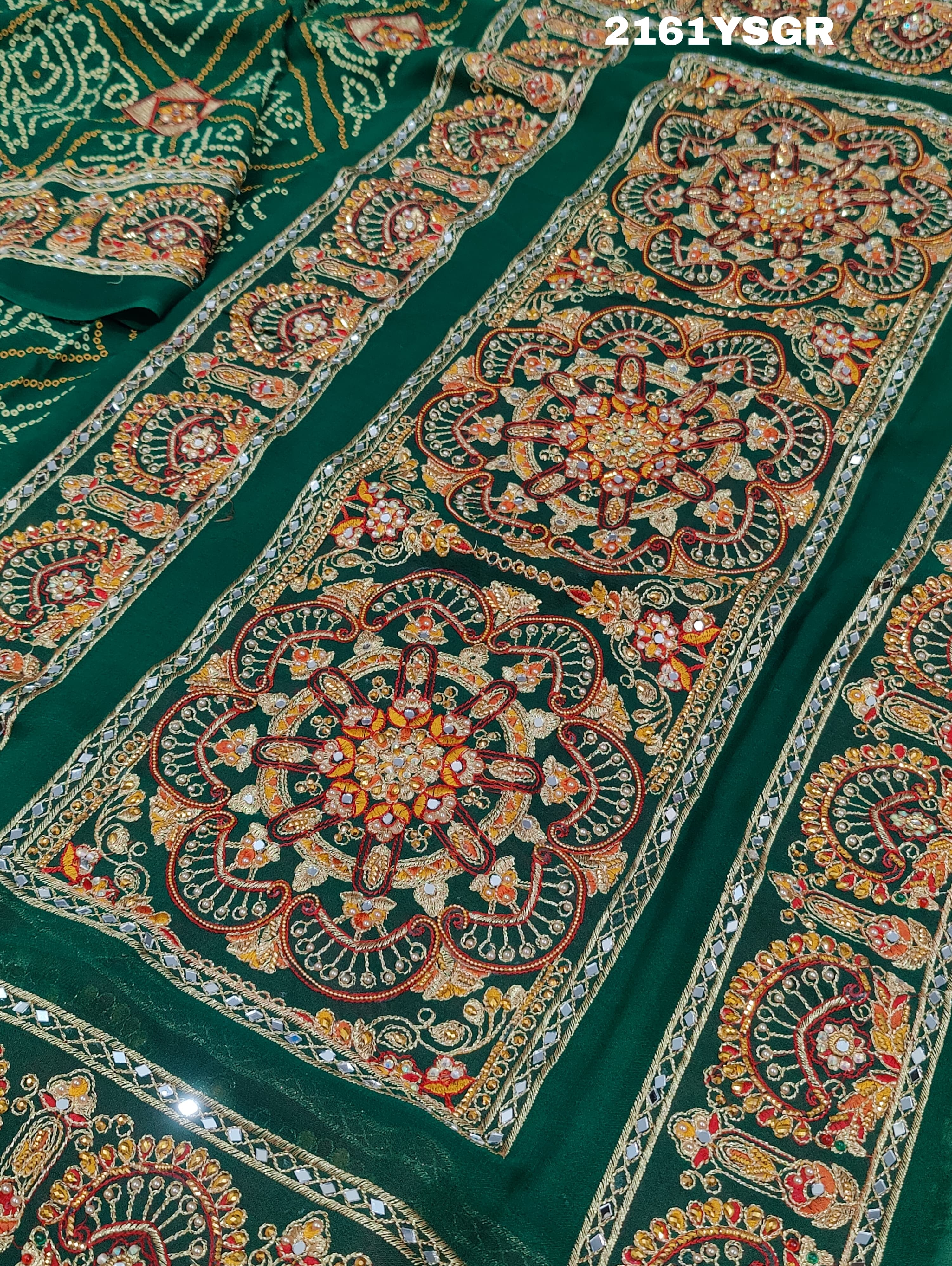 A green saree with red bandhej patterns and royal aari work, along with real mirror work on the border.