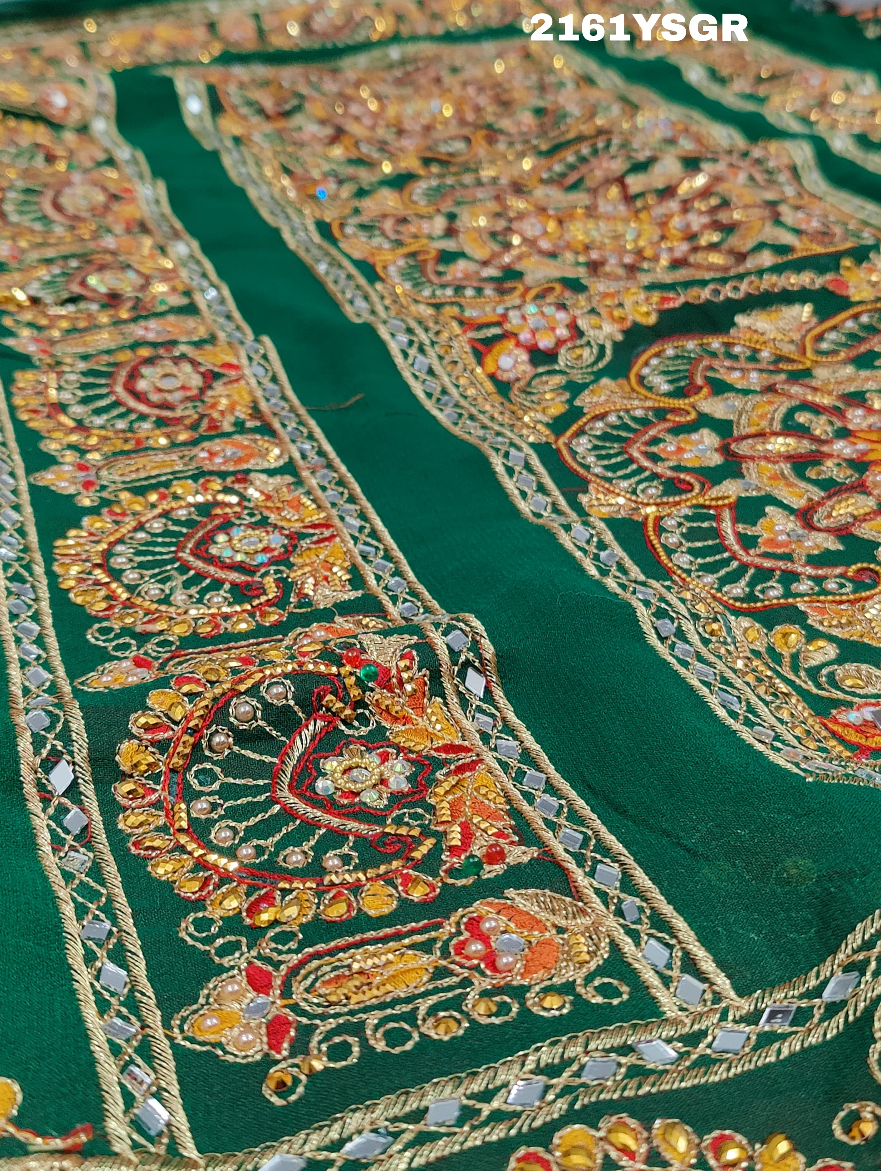 A green saree with red bandhej patterns and royal aari work, along with real mirror work on the border.