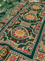 A green bandhej saree with royal aari and real mirror work, displayed on a surface.
