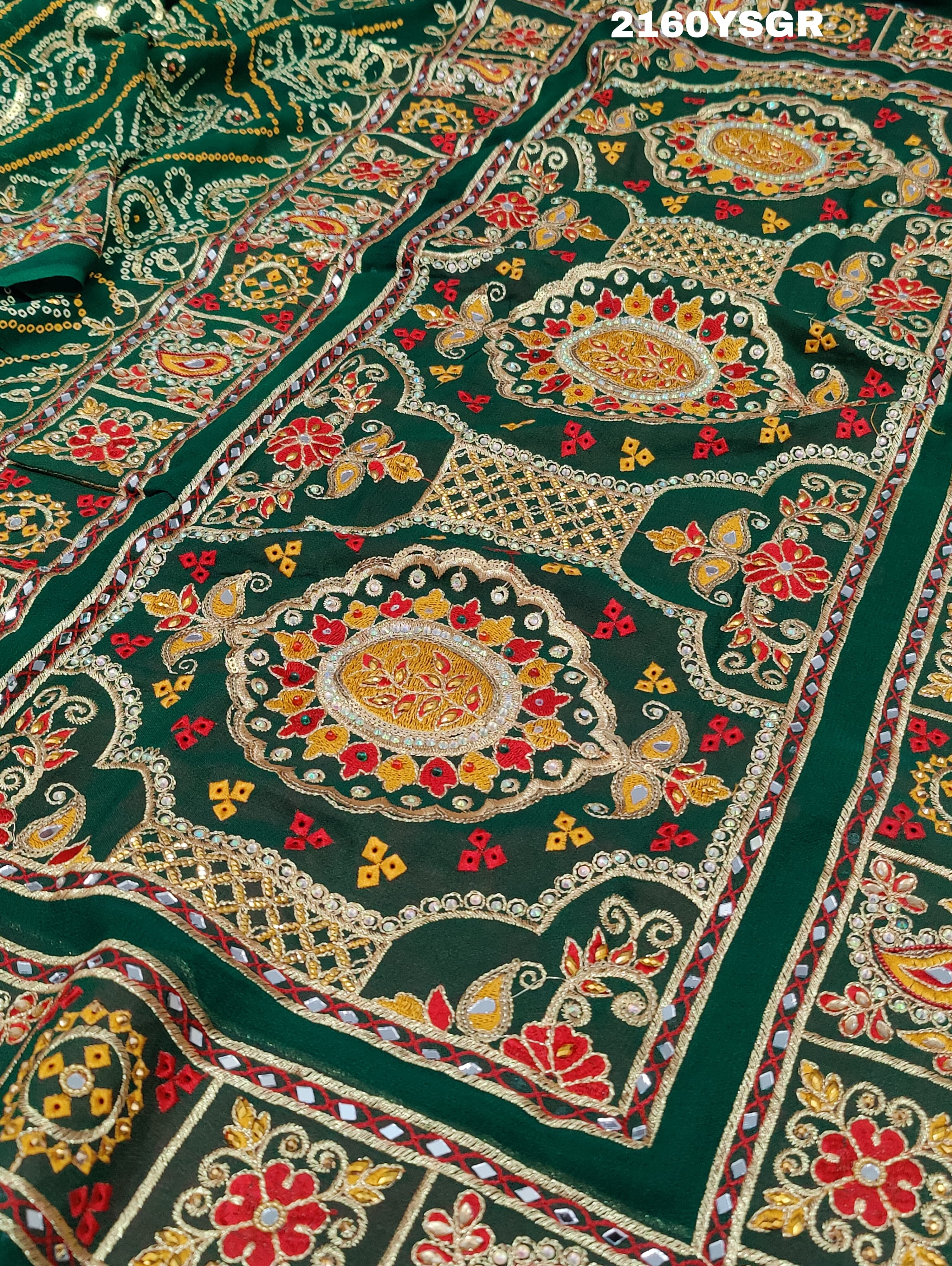 A green bandhej saree with royal aari and real mirror work, displayed on a surface.