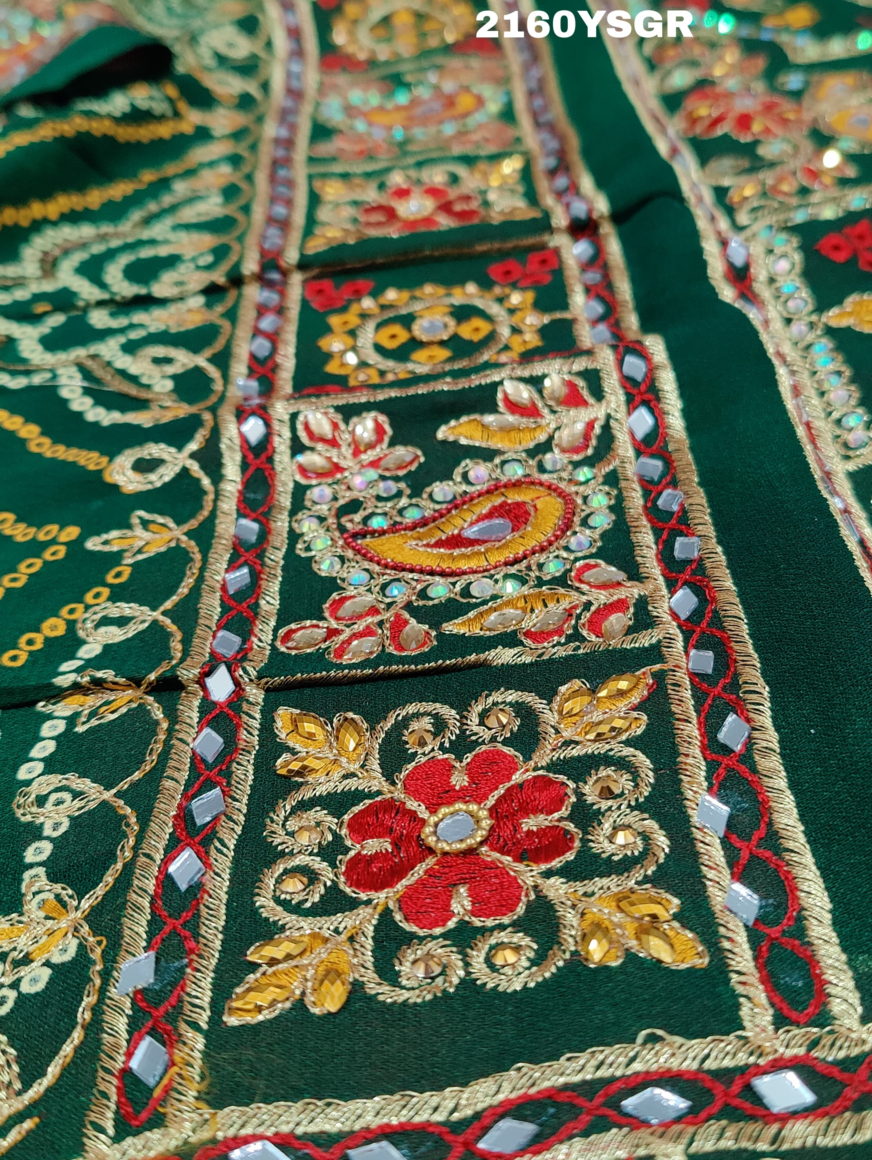 A green bandhej saree with royal aari and real mirror work, displayed on a surface.