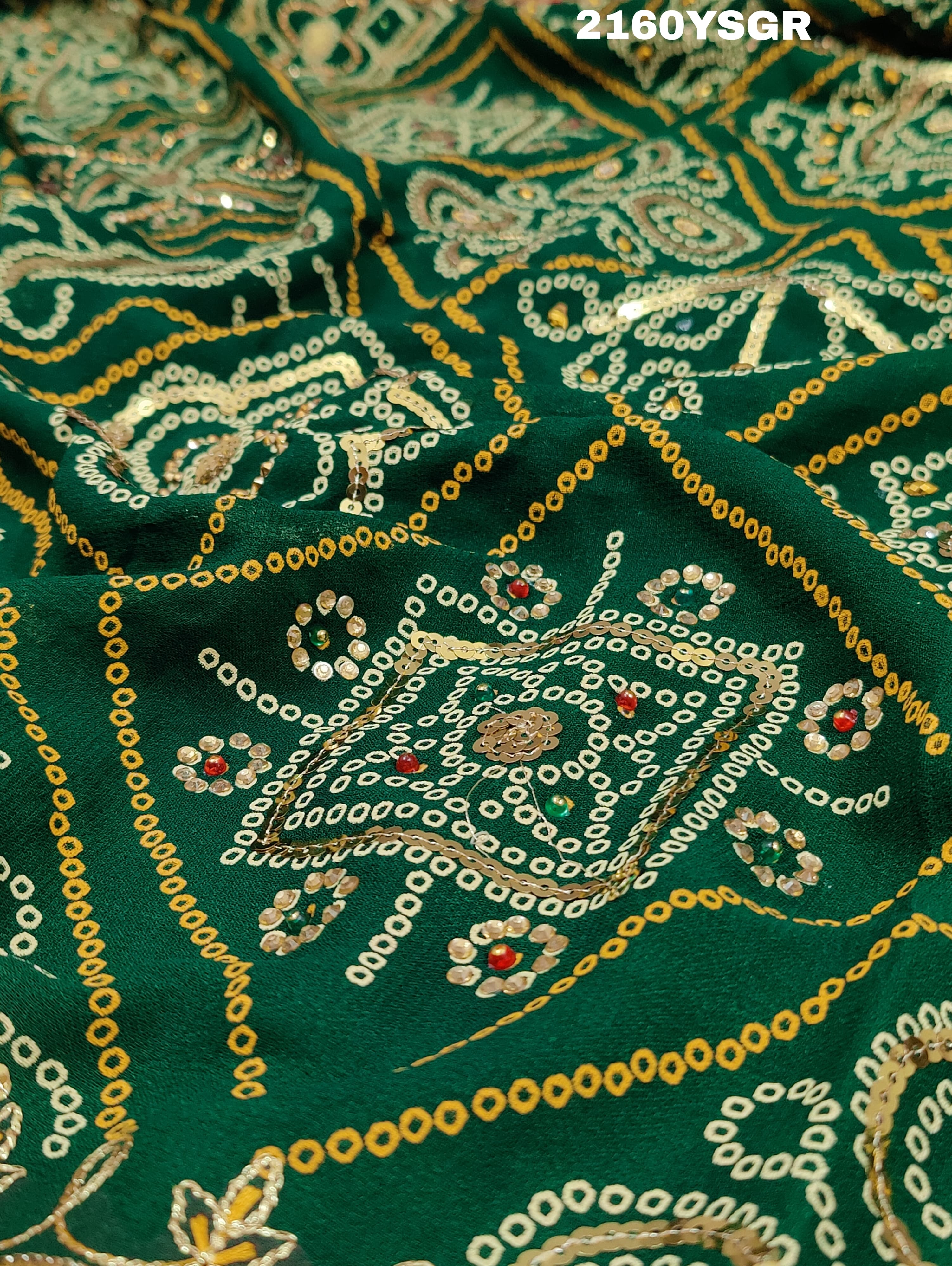A green bandhej saree with royal aari and real mirror work, displayed on a surface.